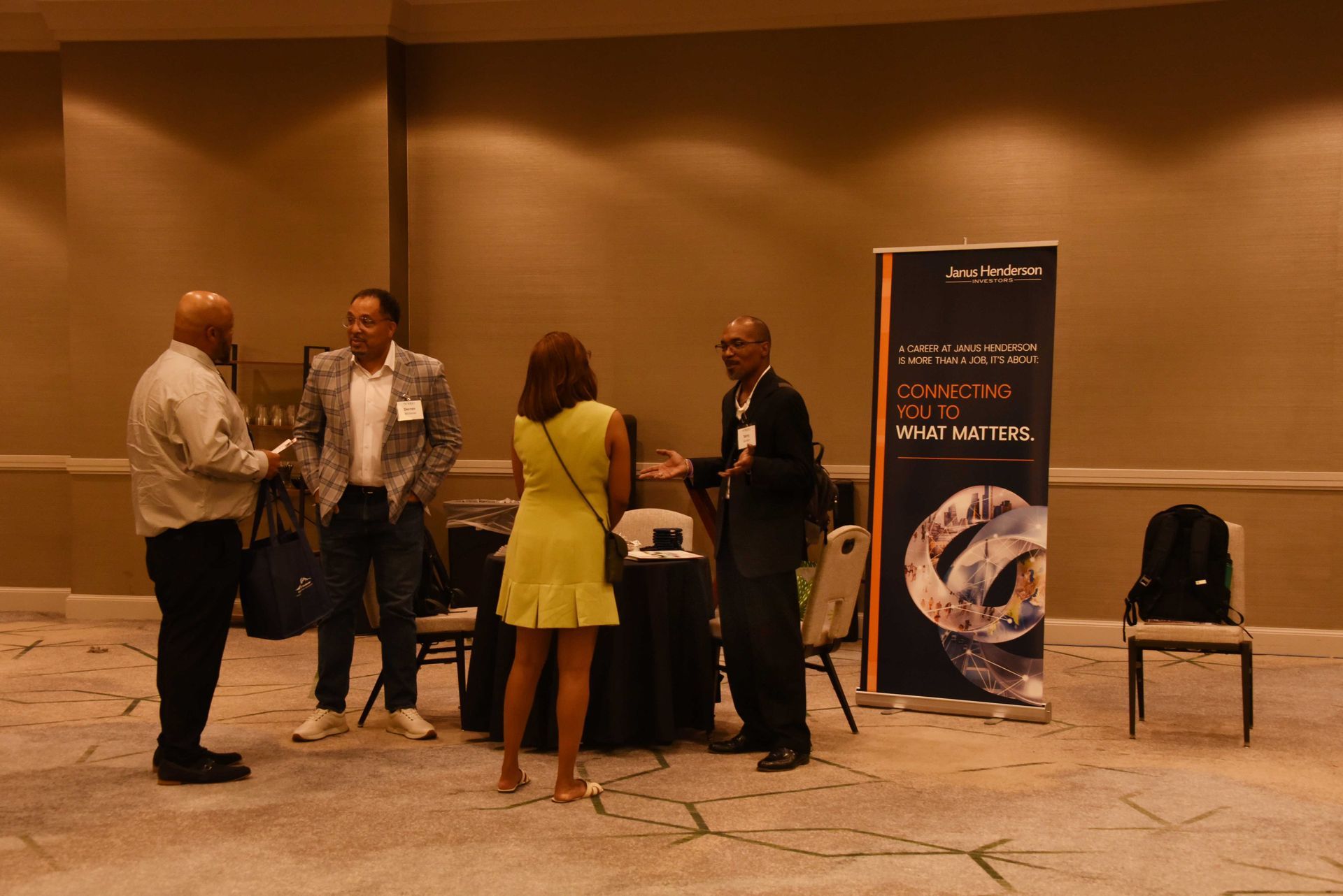 A group of people are standing in a room talking to each other.