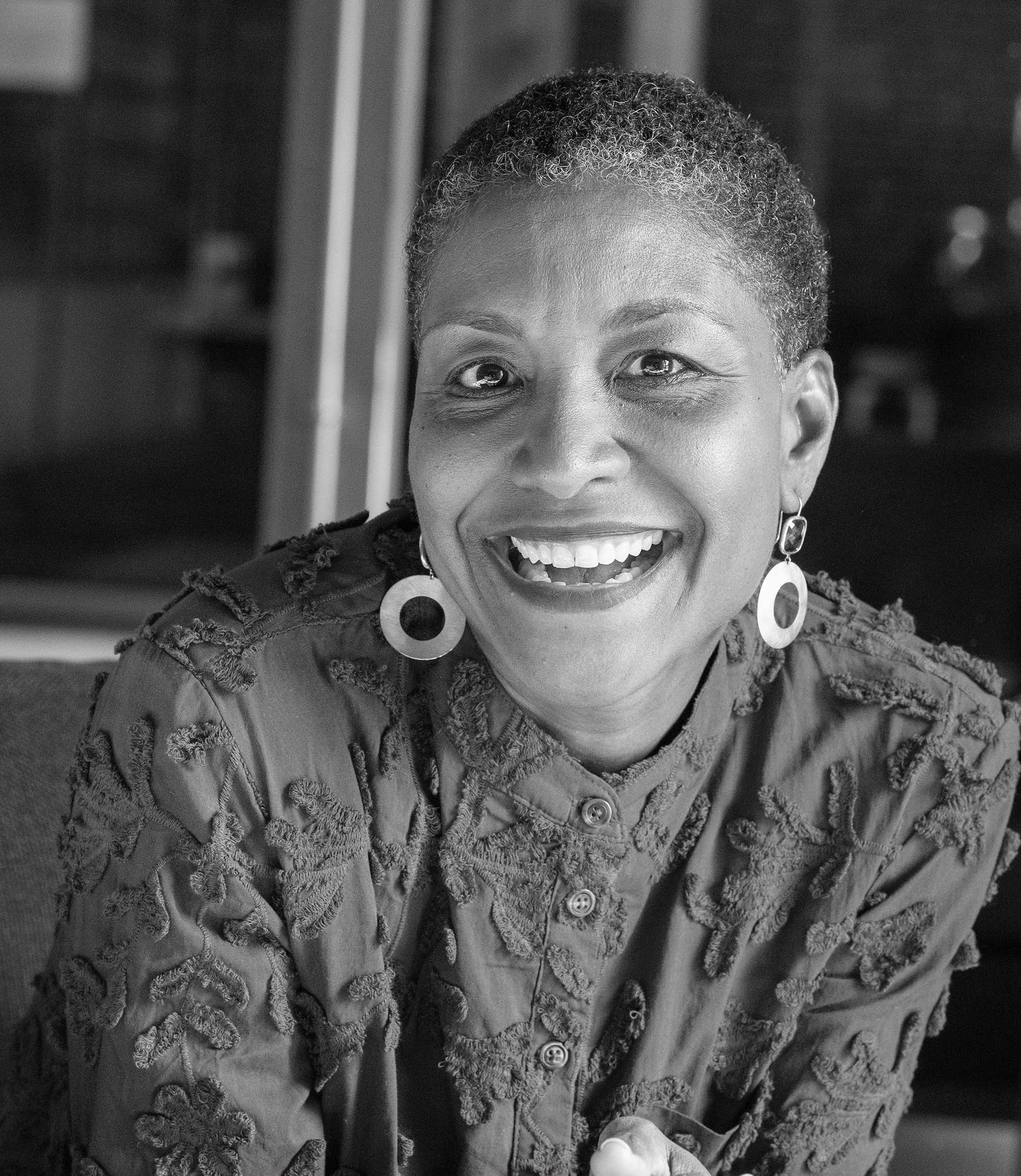 A black and white photo of a woman wearing earrings and smiling.