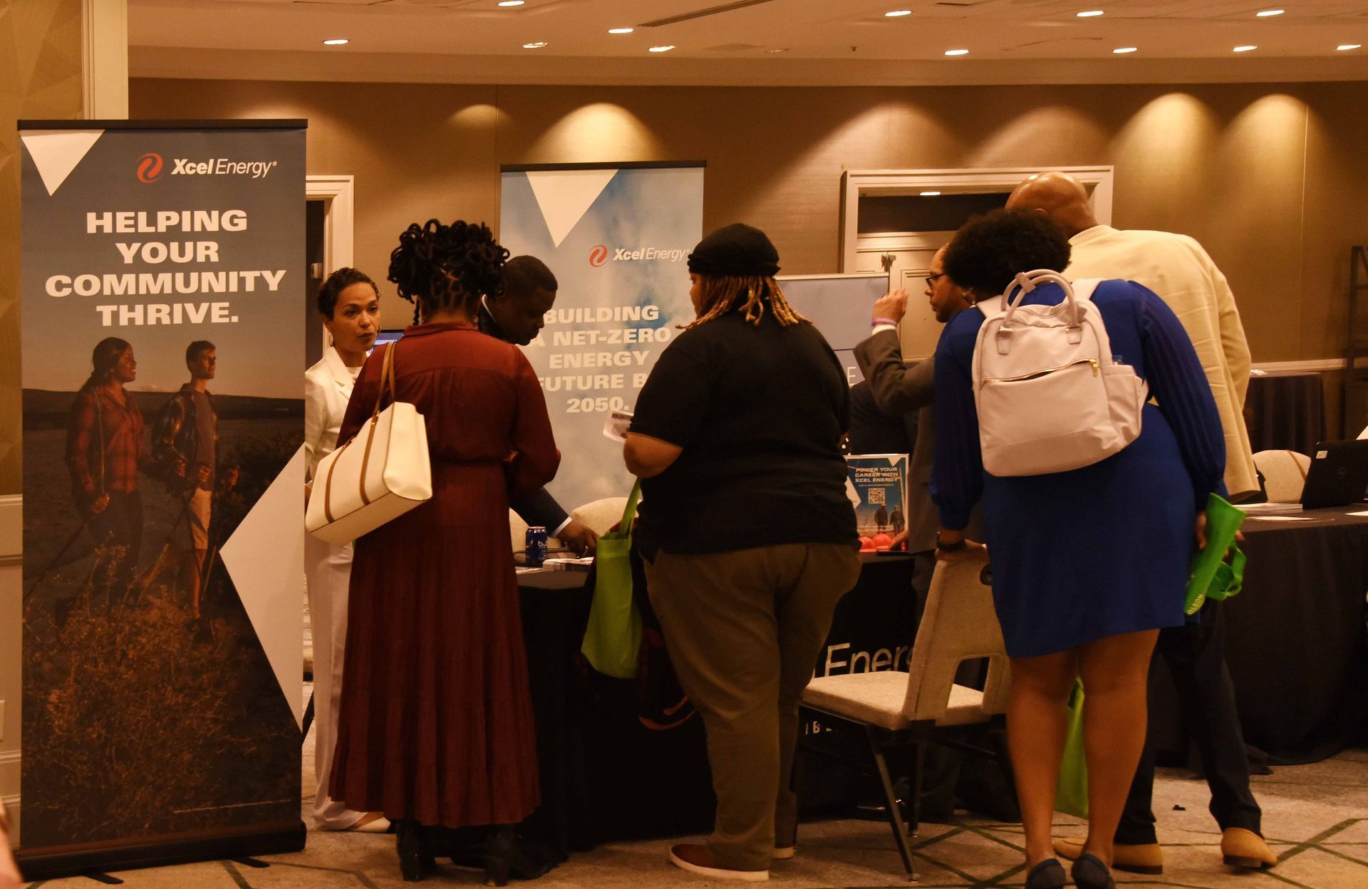 A group of people are standing around a table in front of a sign that says helping your community thrive.