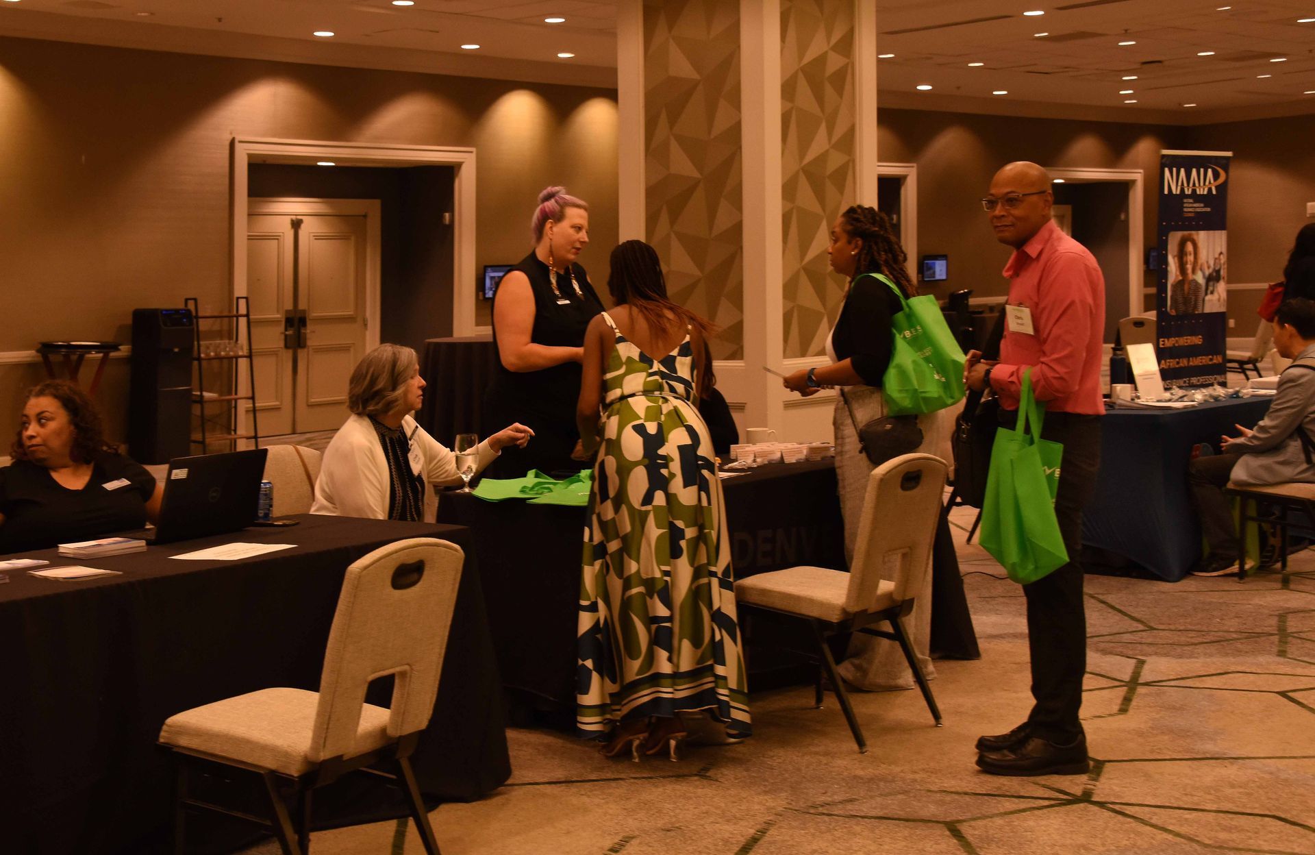 A group of people are standing around tables in a room.