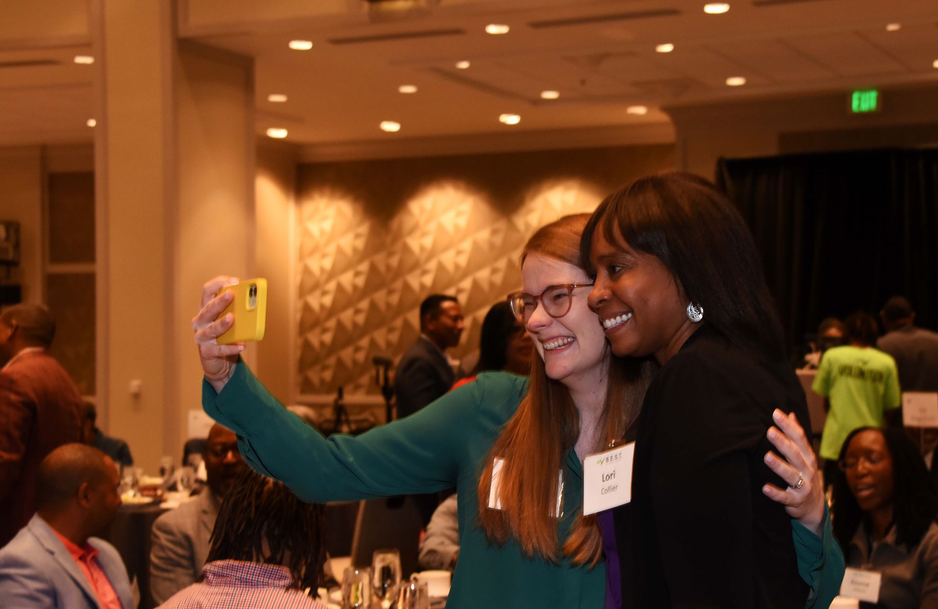 Two women are taking a selfie together at a conference.