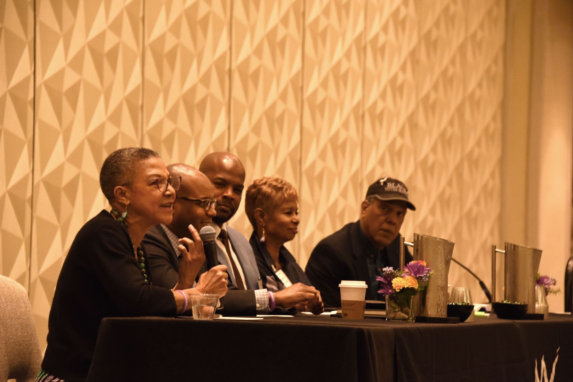 A group of people are sitting at a table talking into microphones.