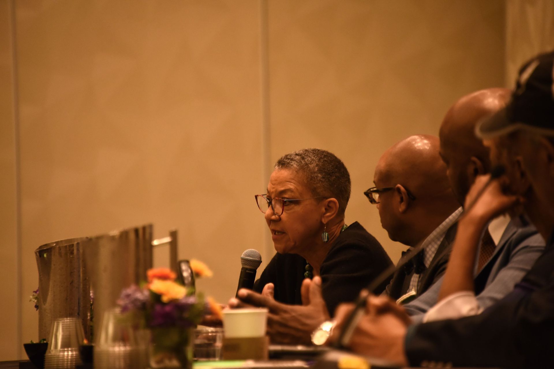 A group of people are sitting at a table talking into microphones.