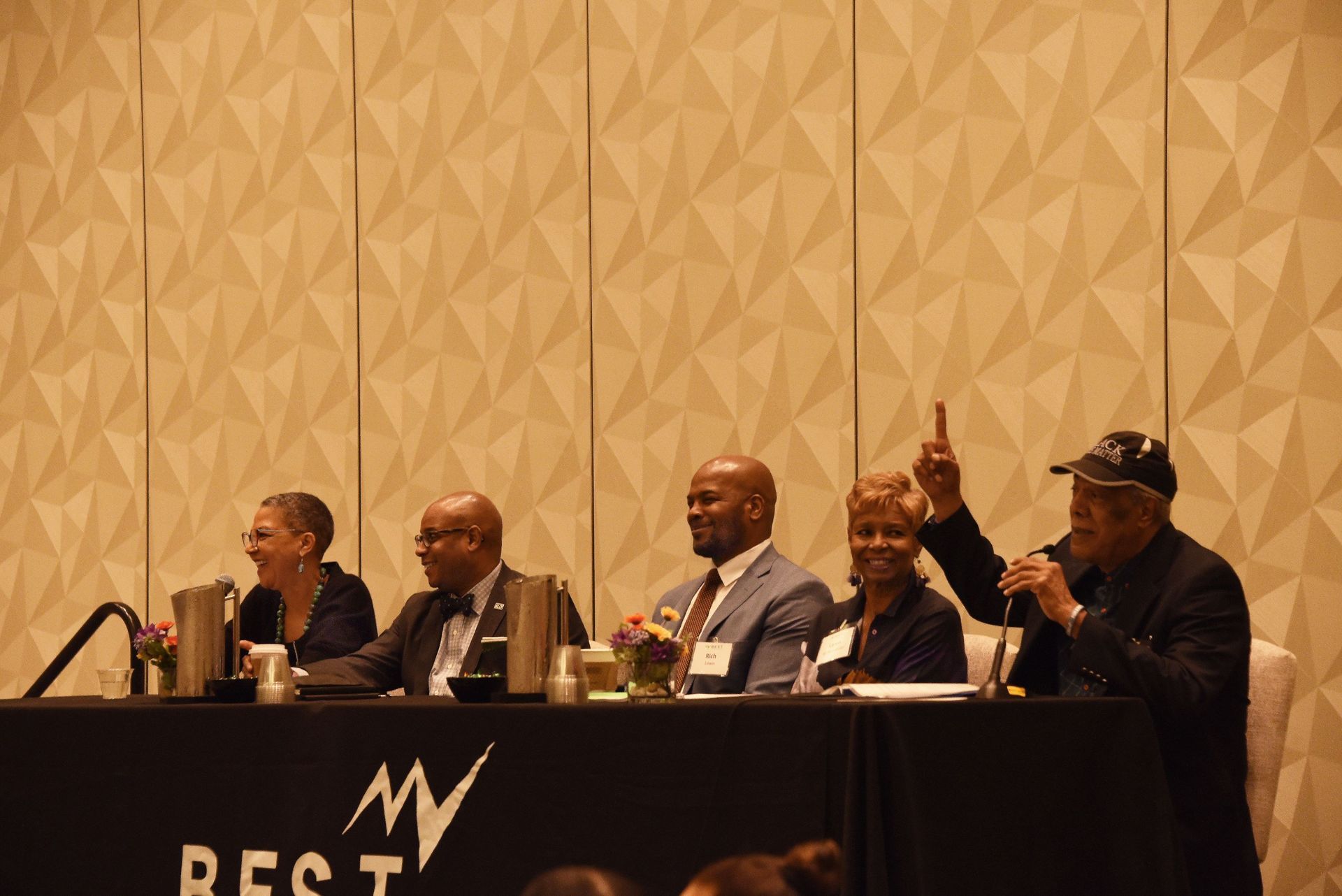A group of people are sitting at a table with a microphone.