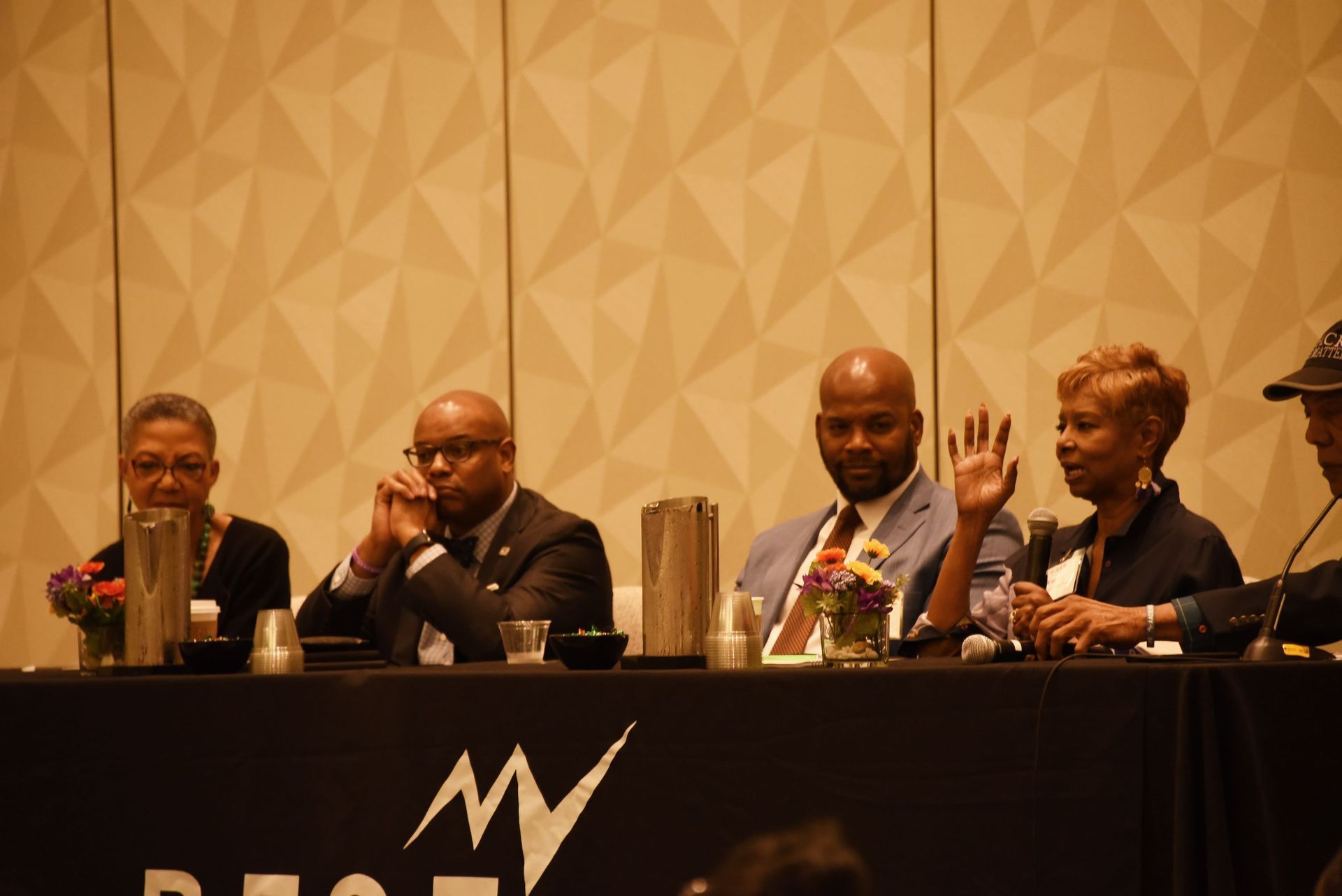 A group of people are sitting at a table in front of a microphone.