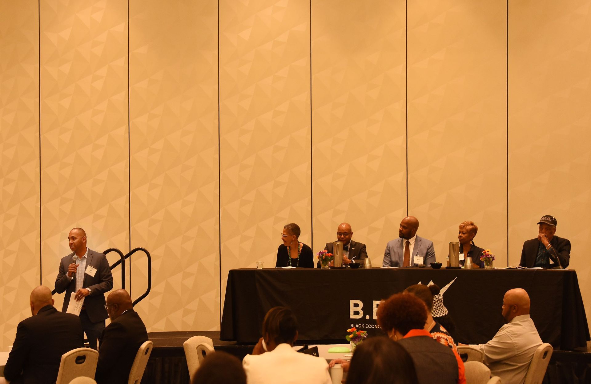 A group of people sitting at a table with a sign that says b.f.