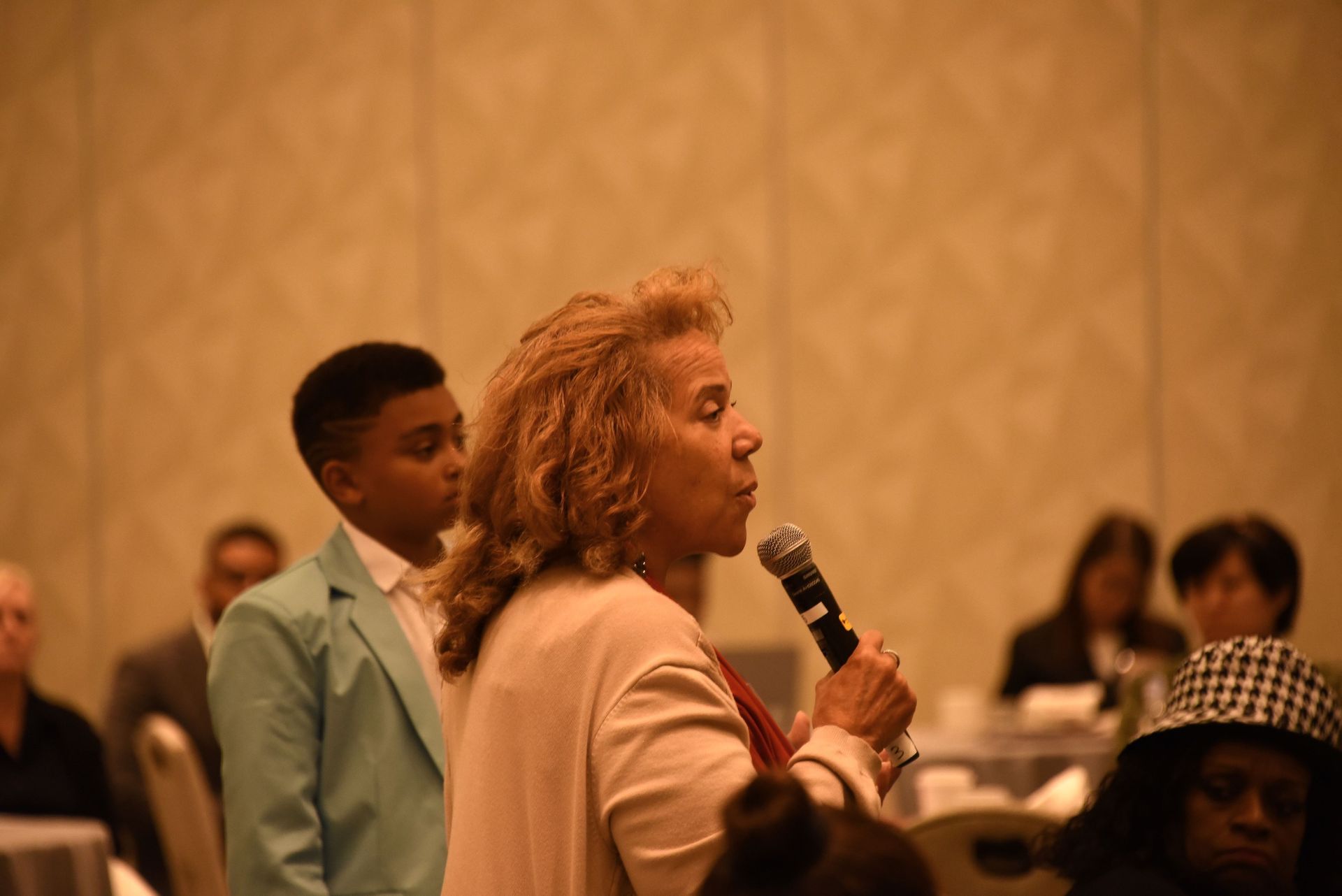 A woman is holding a microphone in front of a group of people.