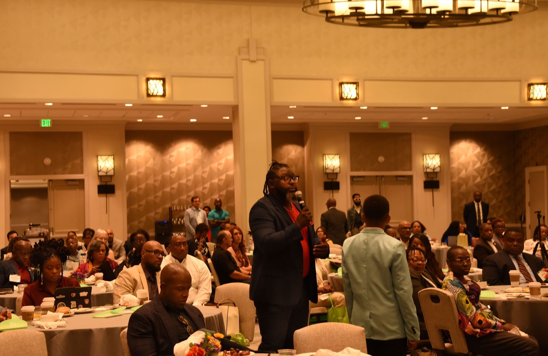 A group of people are sitting at tables in a large room