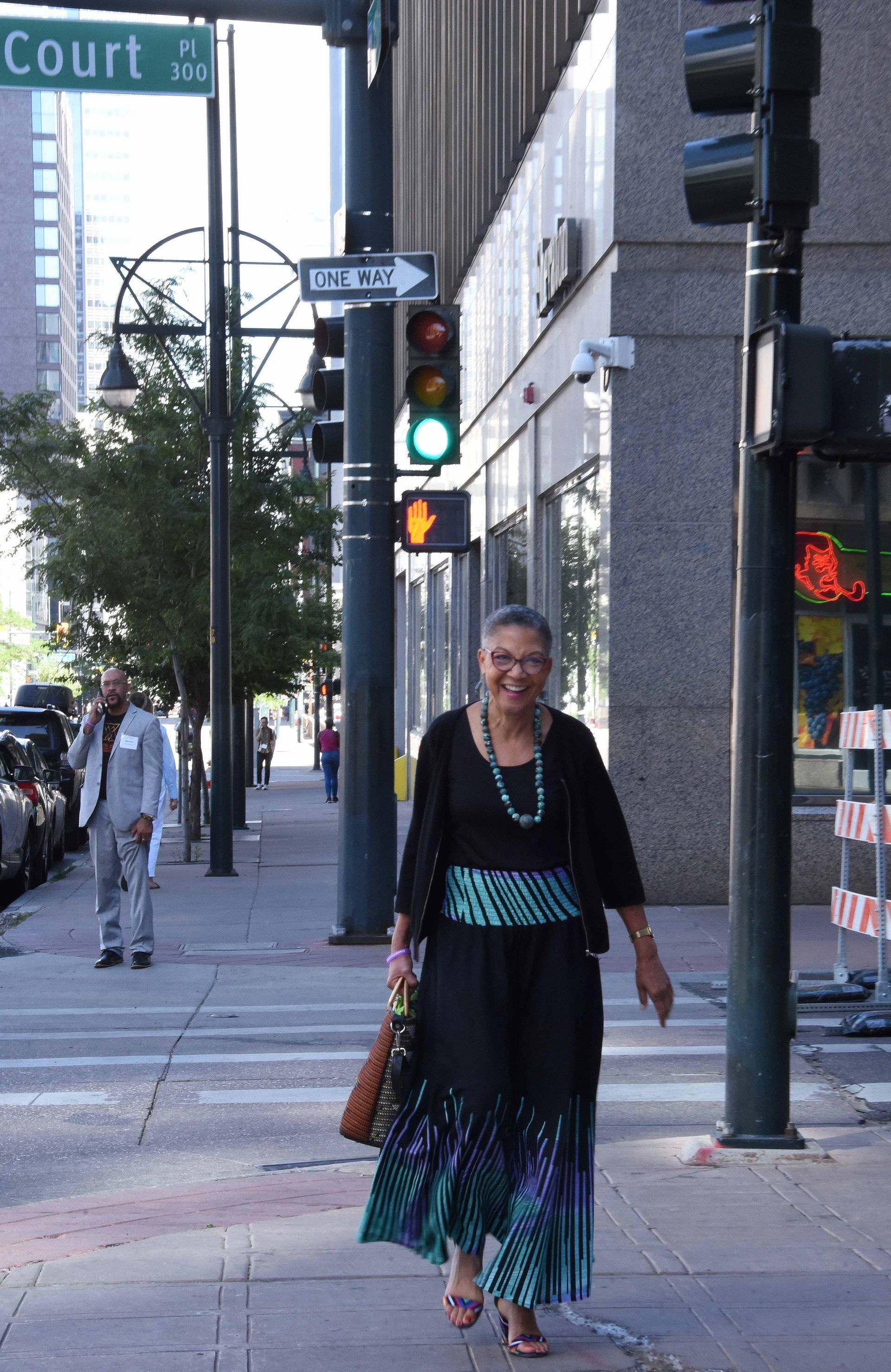 A woman is crossing a street in front of a sign that says court