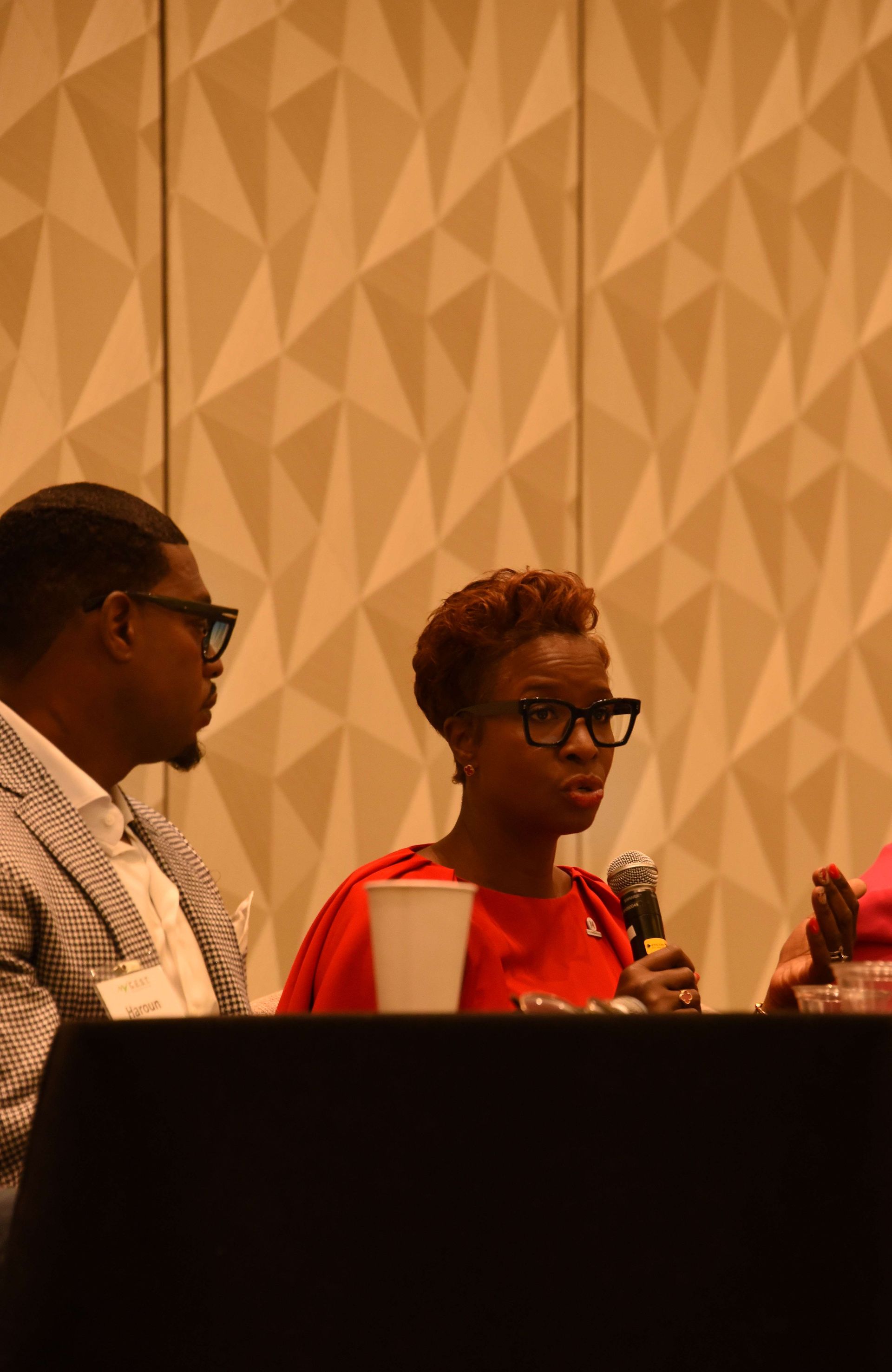 A man and a woman are sitting at a table talking into microphones.