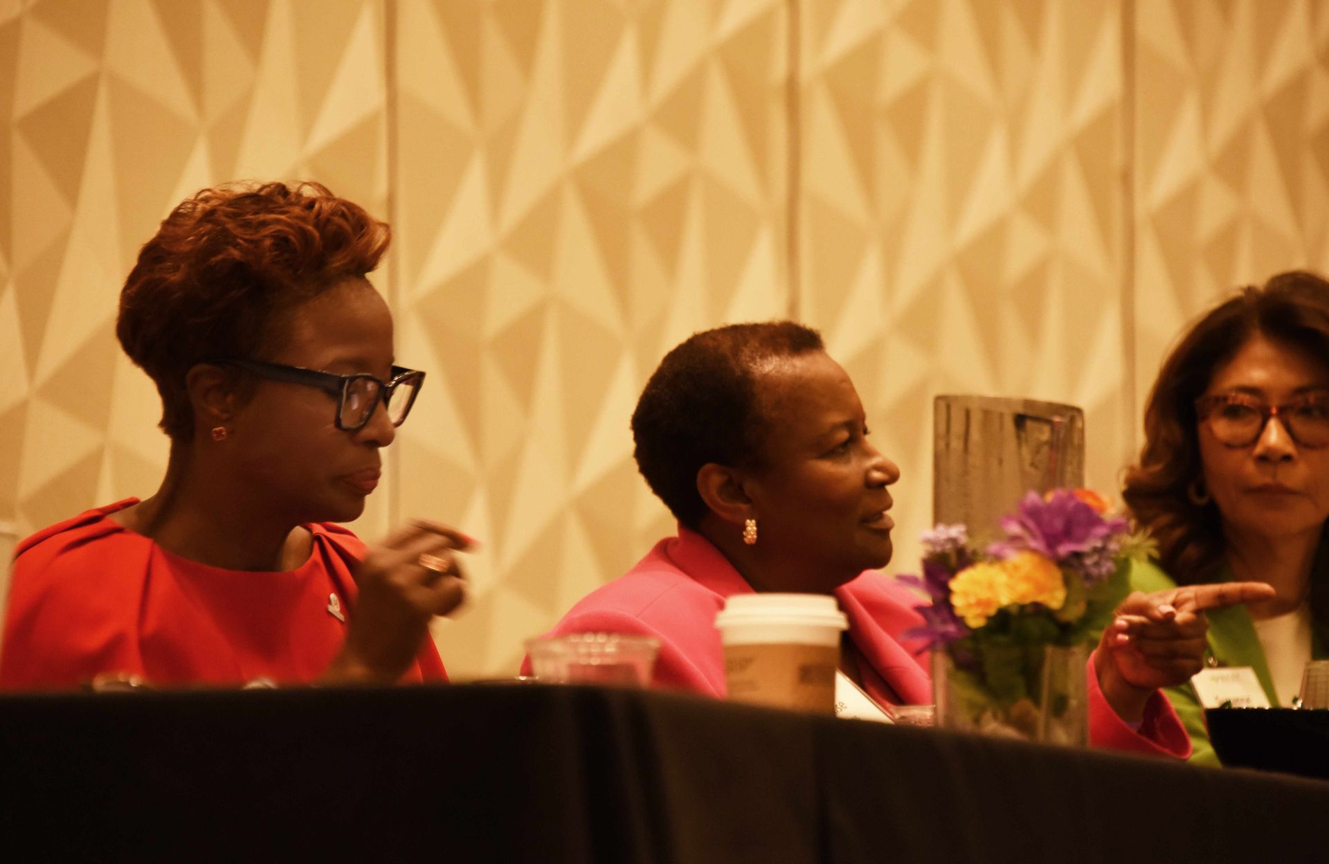 Three women are sitting at a table talking to each other.
