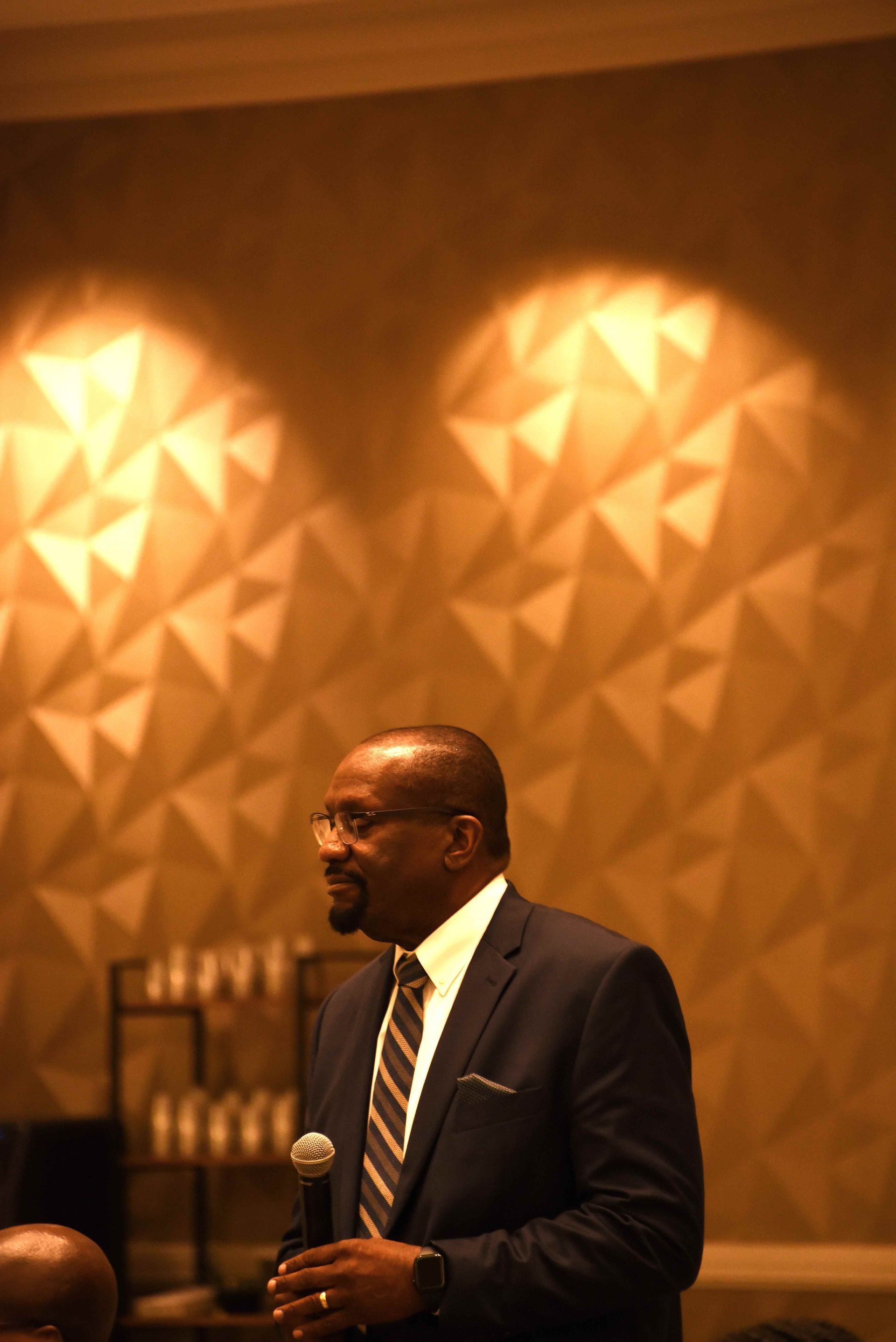 A man in a suit and tie is holding a microphone