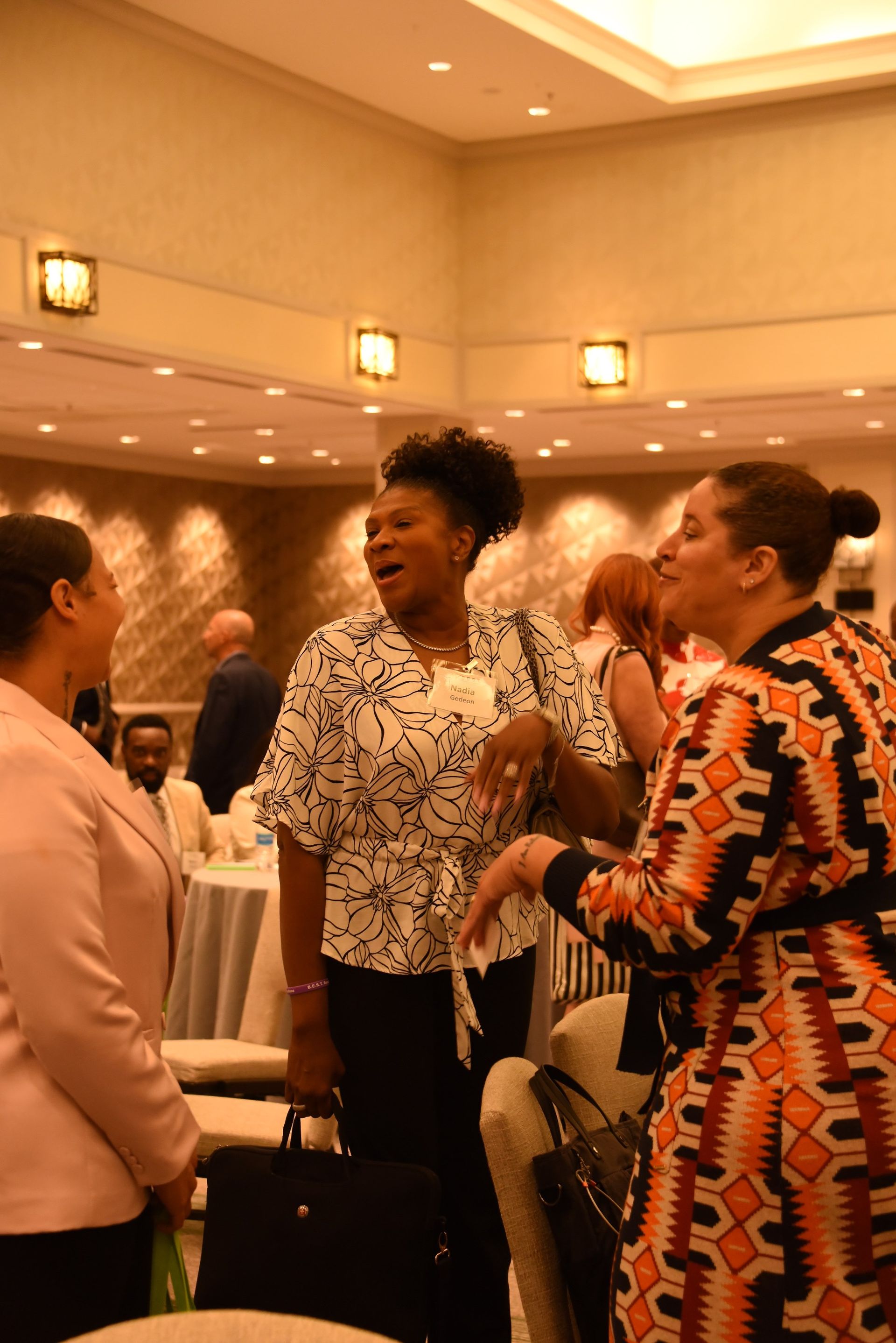 A group of women are standing in a room talking to each other.