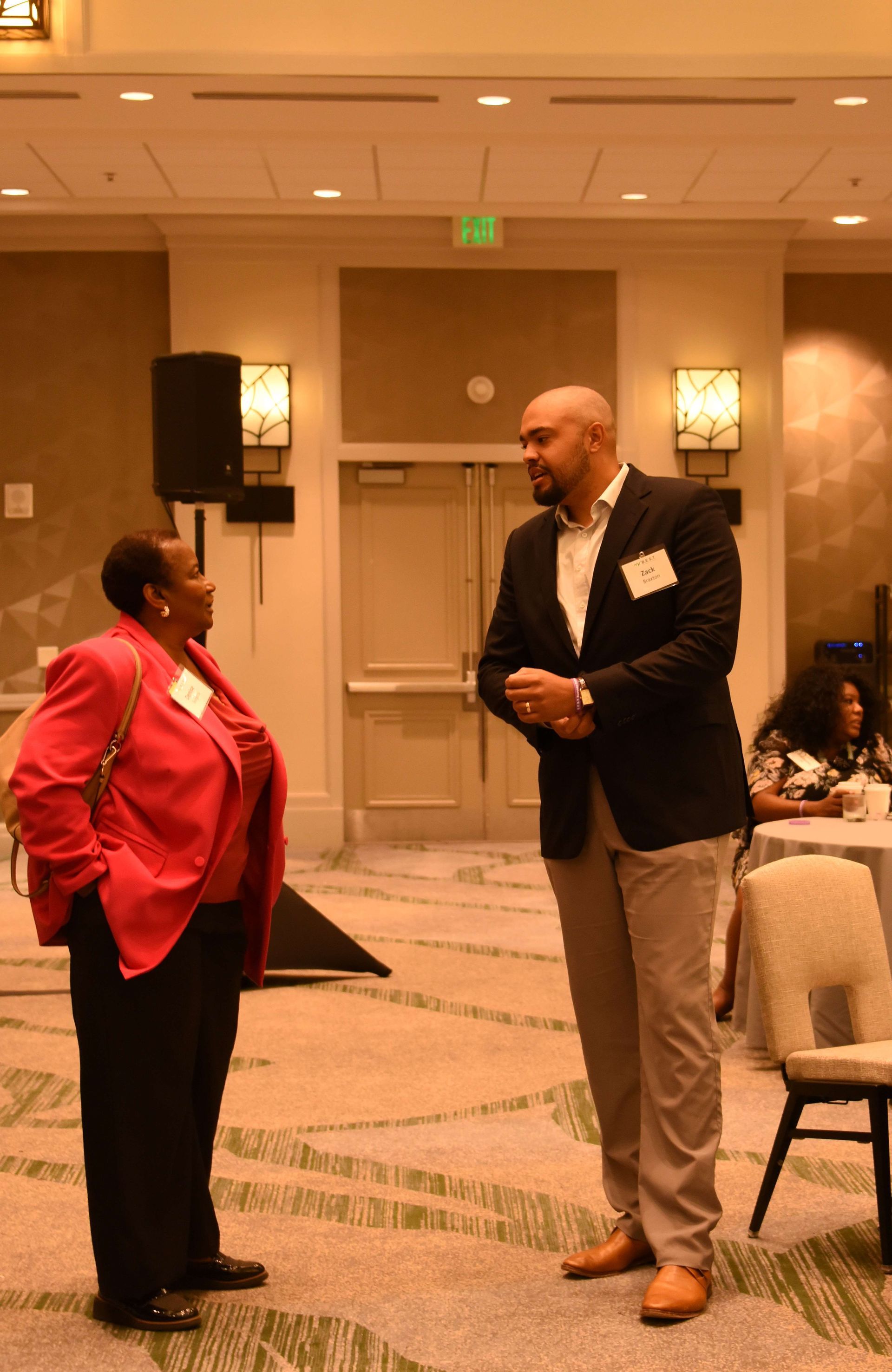 A man and a woman are standing in a room talking to each other.