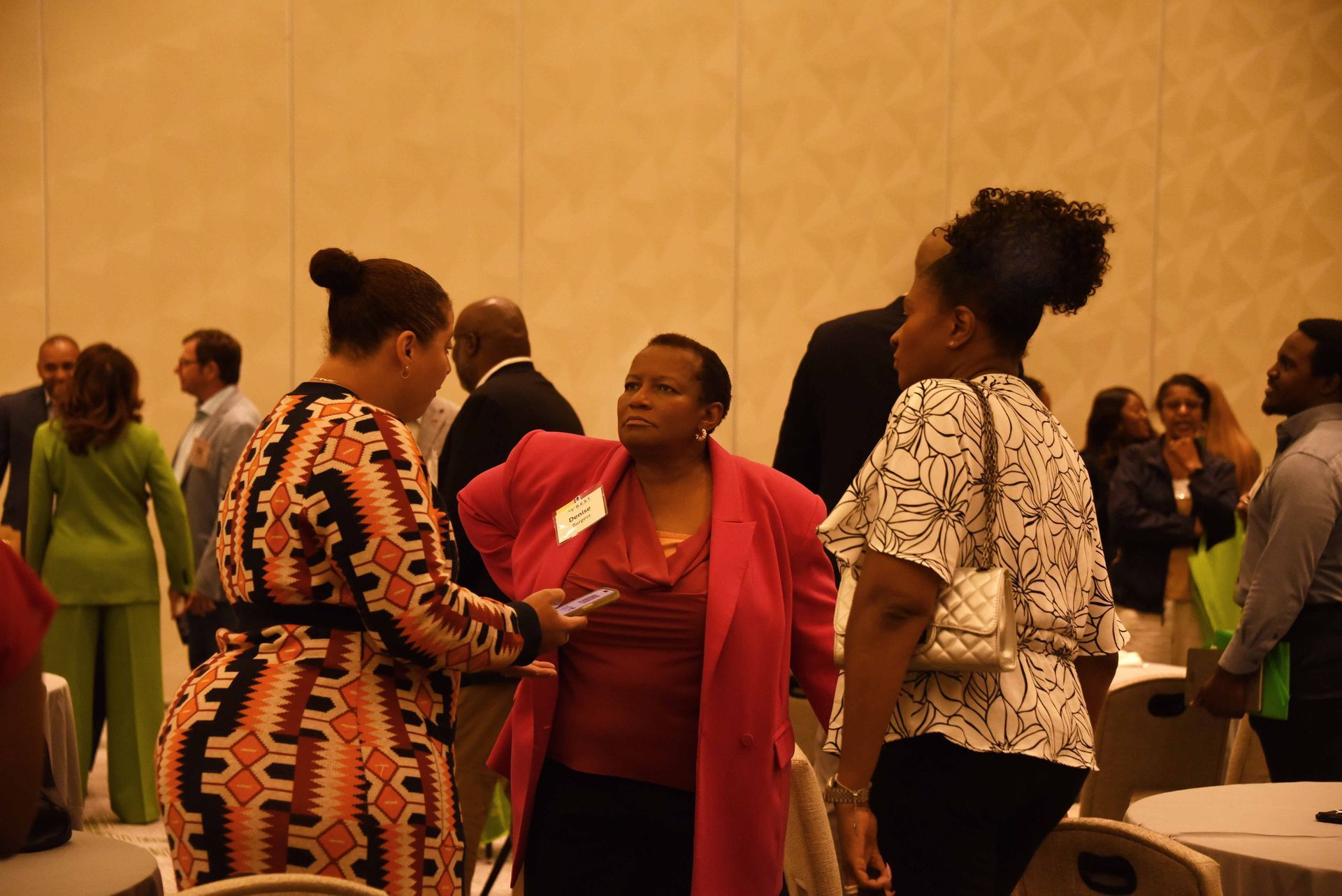 A group of people are standing in a room talking to each other.