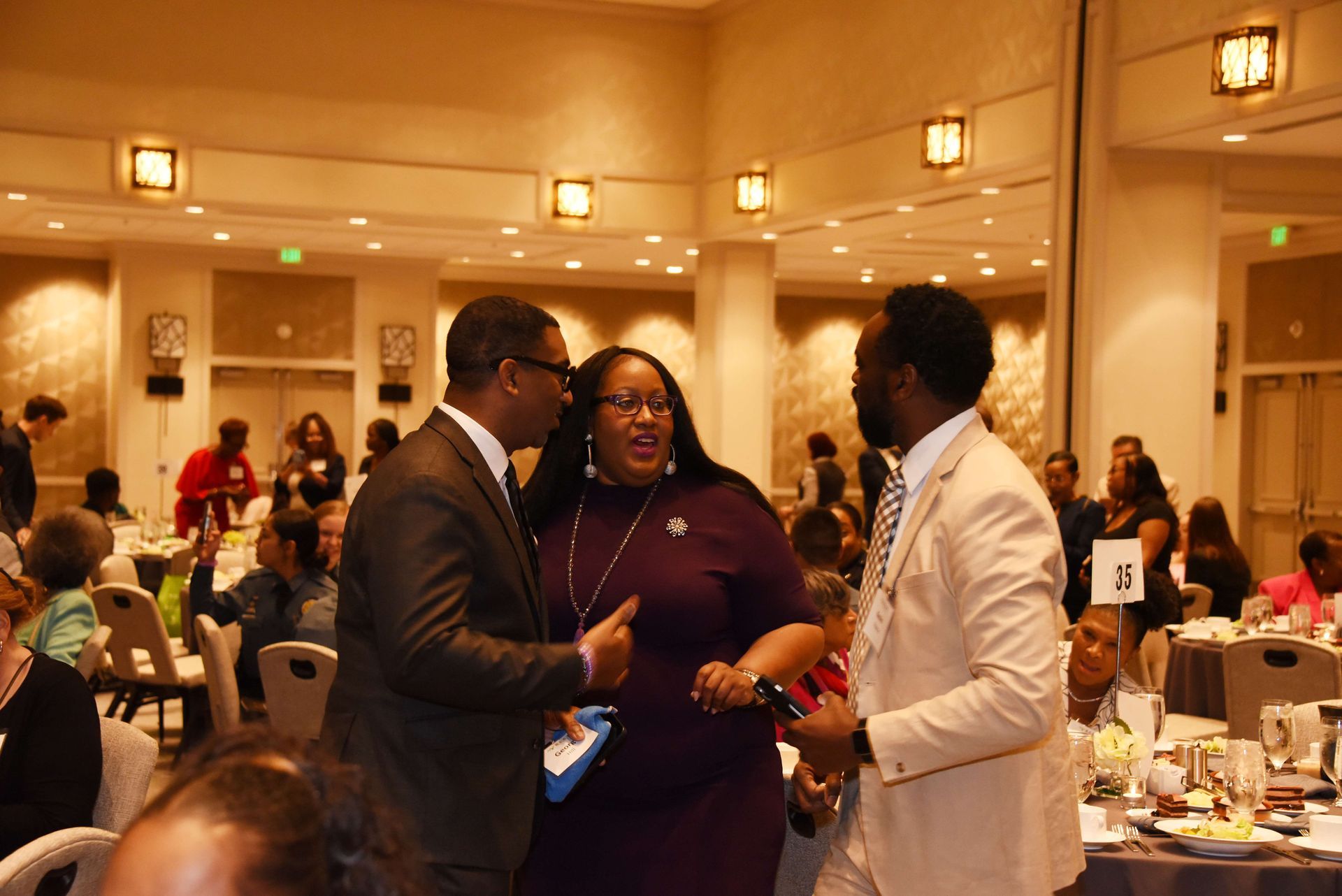 A group of people are standing in a room talking to each other.