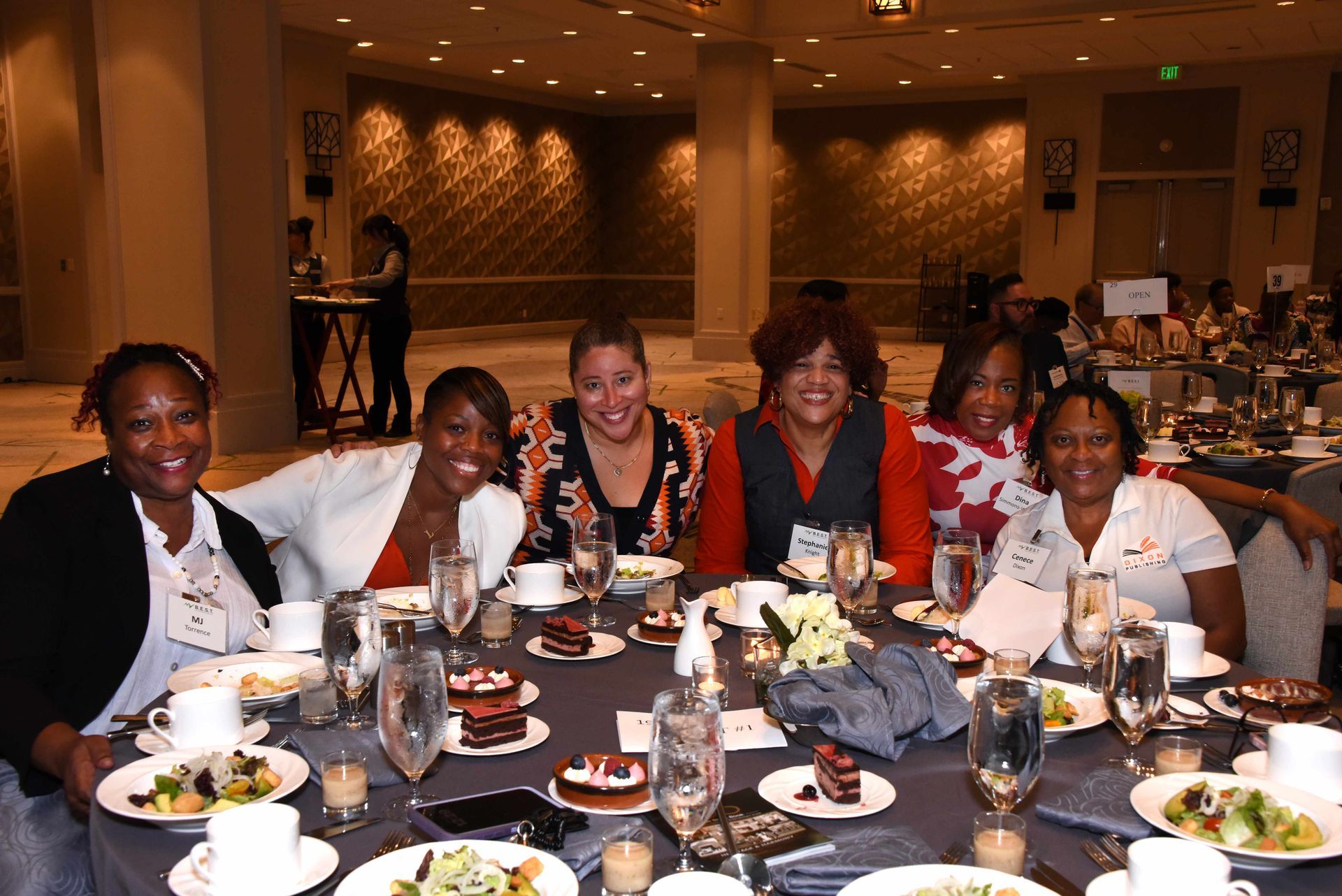 A group of women are sitting at a table with plates of food and wine glasses.