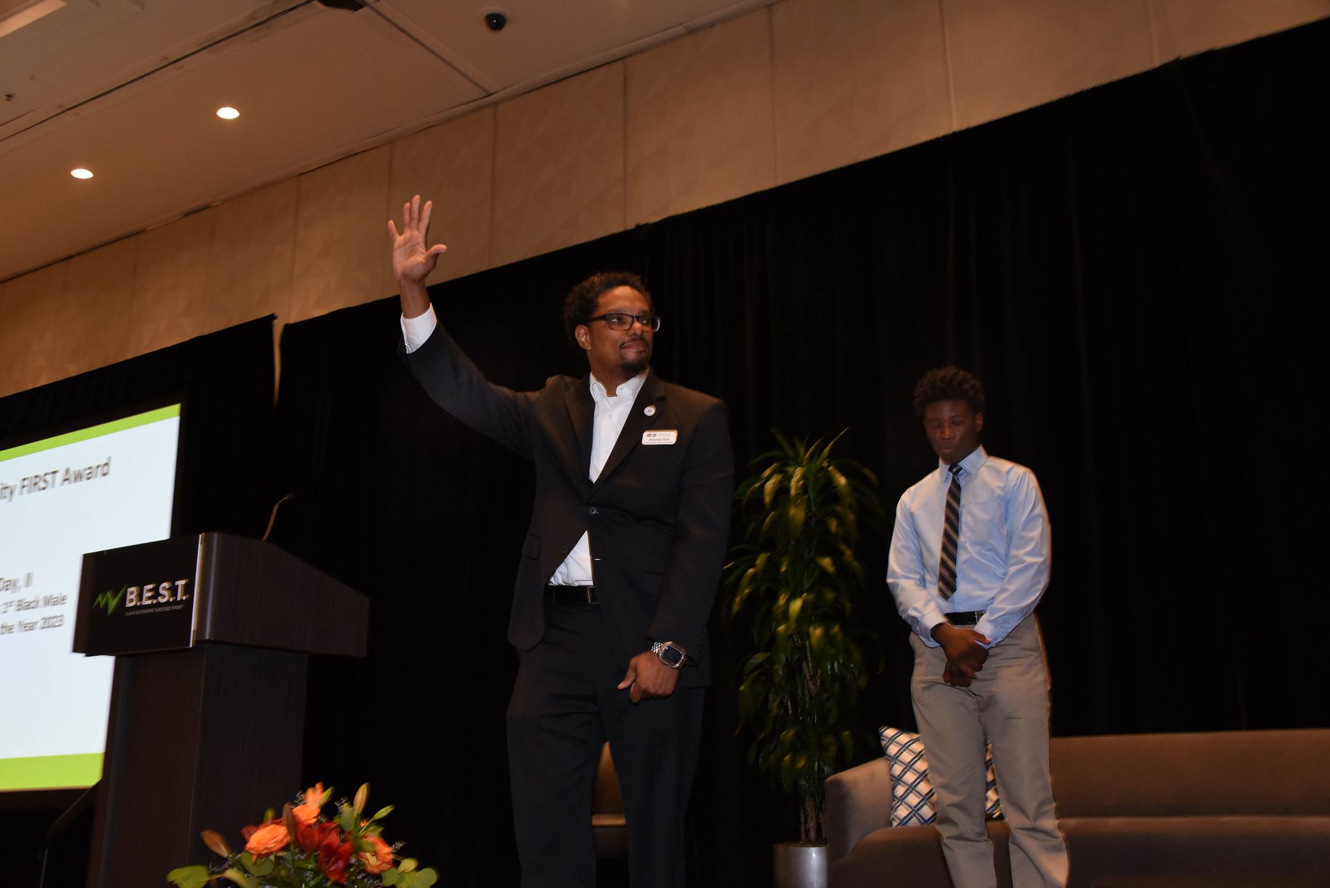 A man in a suit is standing at a podium giving a presentation.