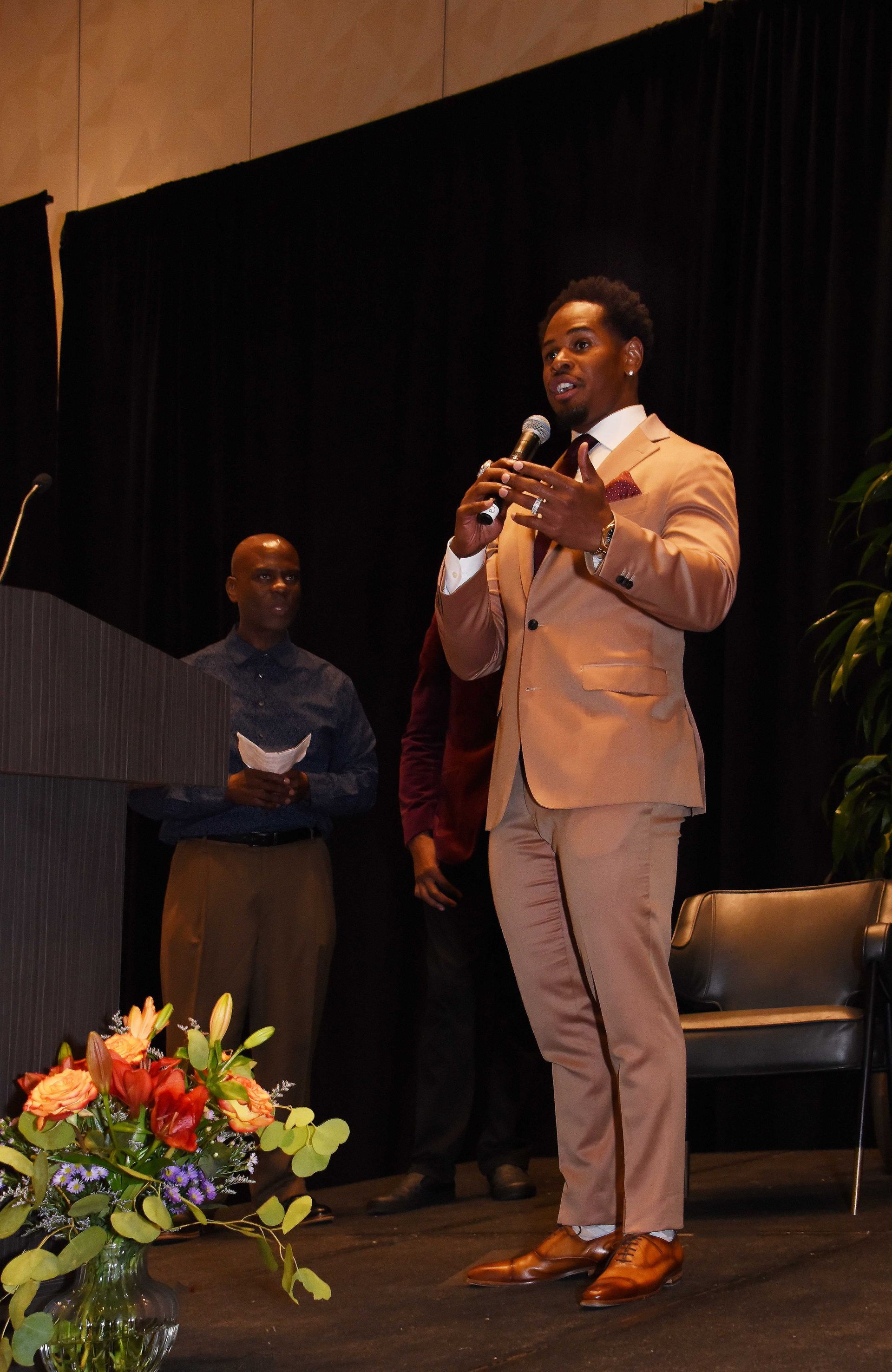 A man in a suit is speaking into a microphone