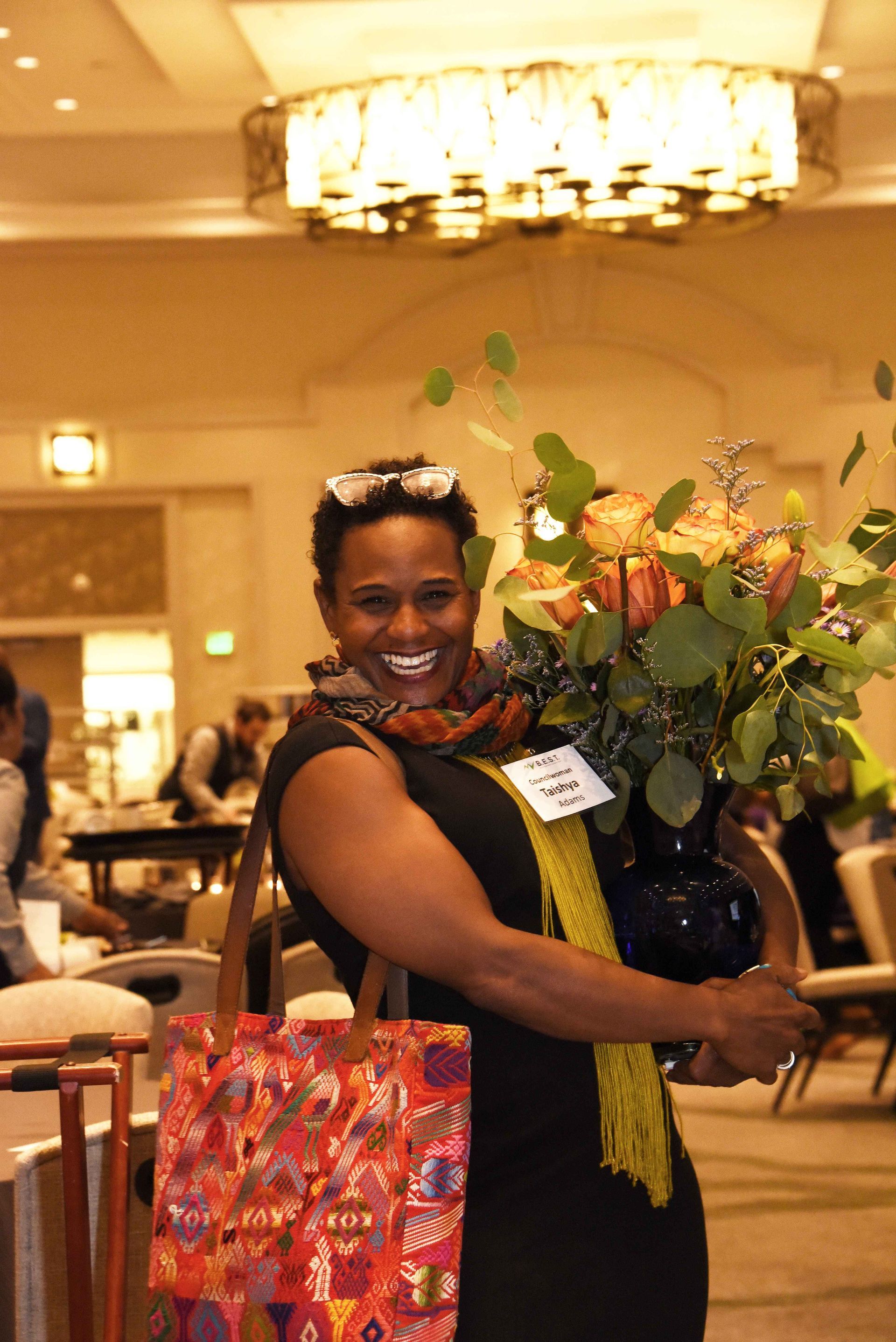 A woman in a black dress is holding a vase of flowers