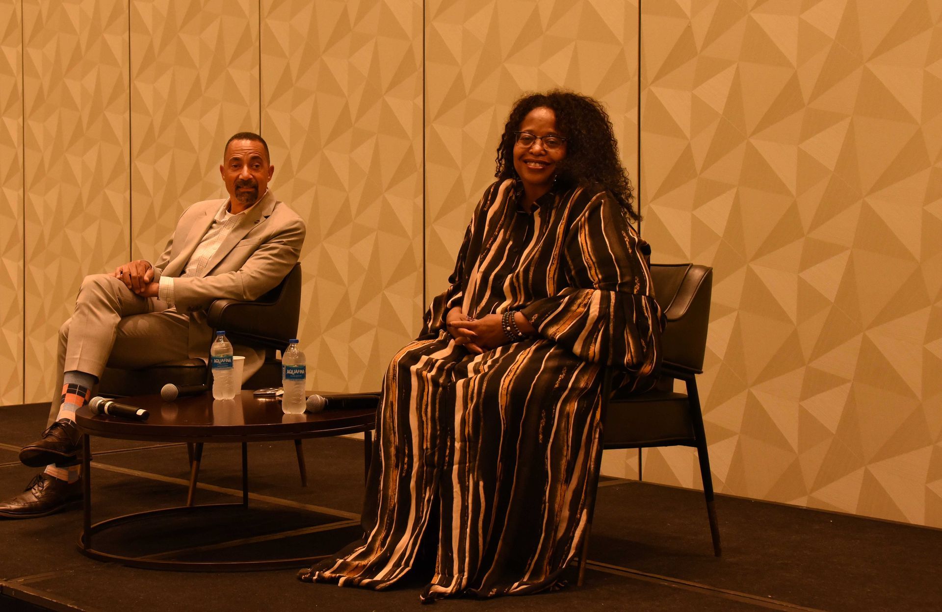 A man and a woman are sitting next to each other on a stage.