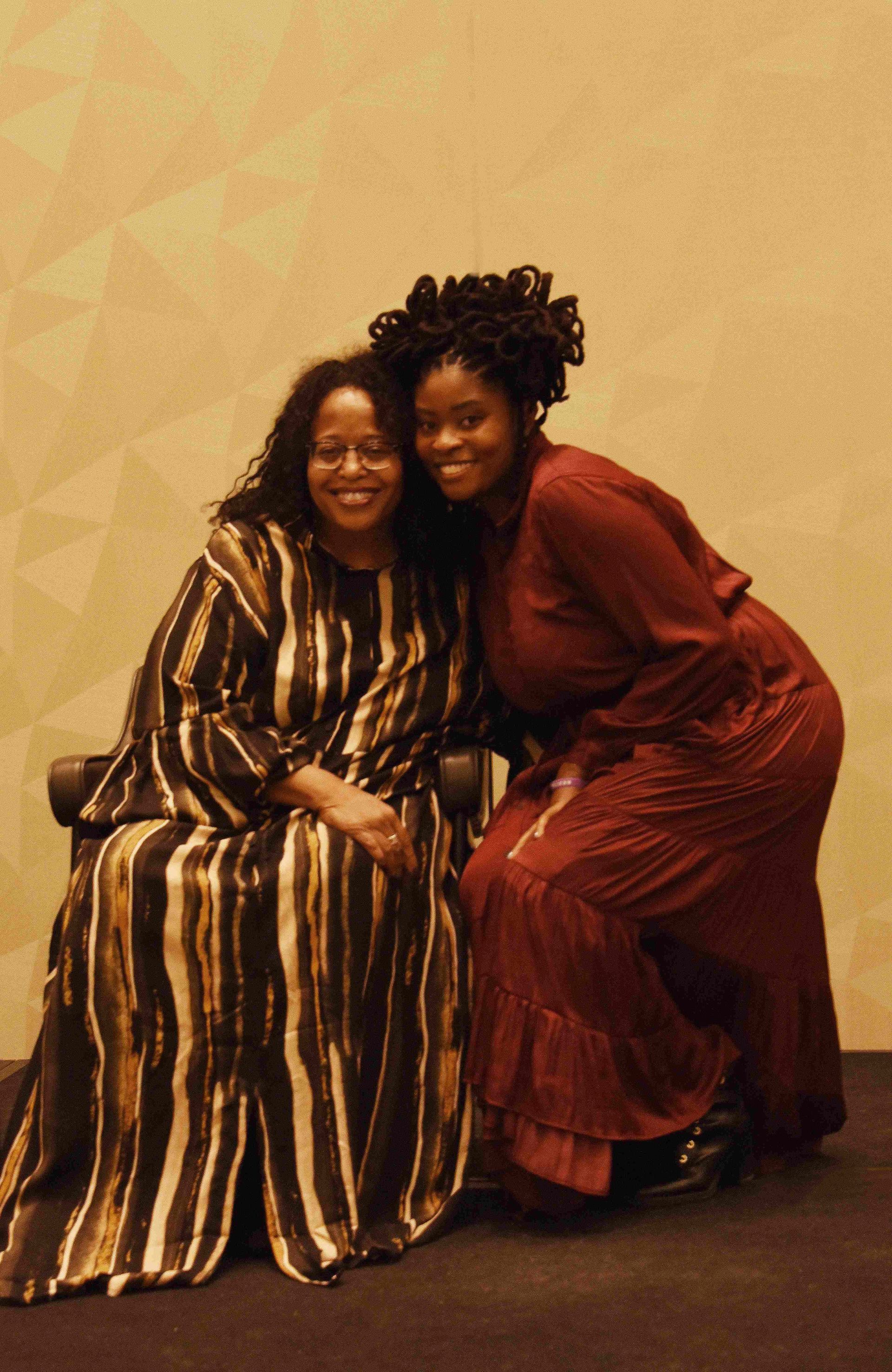 Two women in striped dresses are posing for a picture.