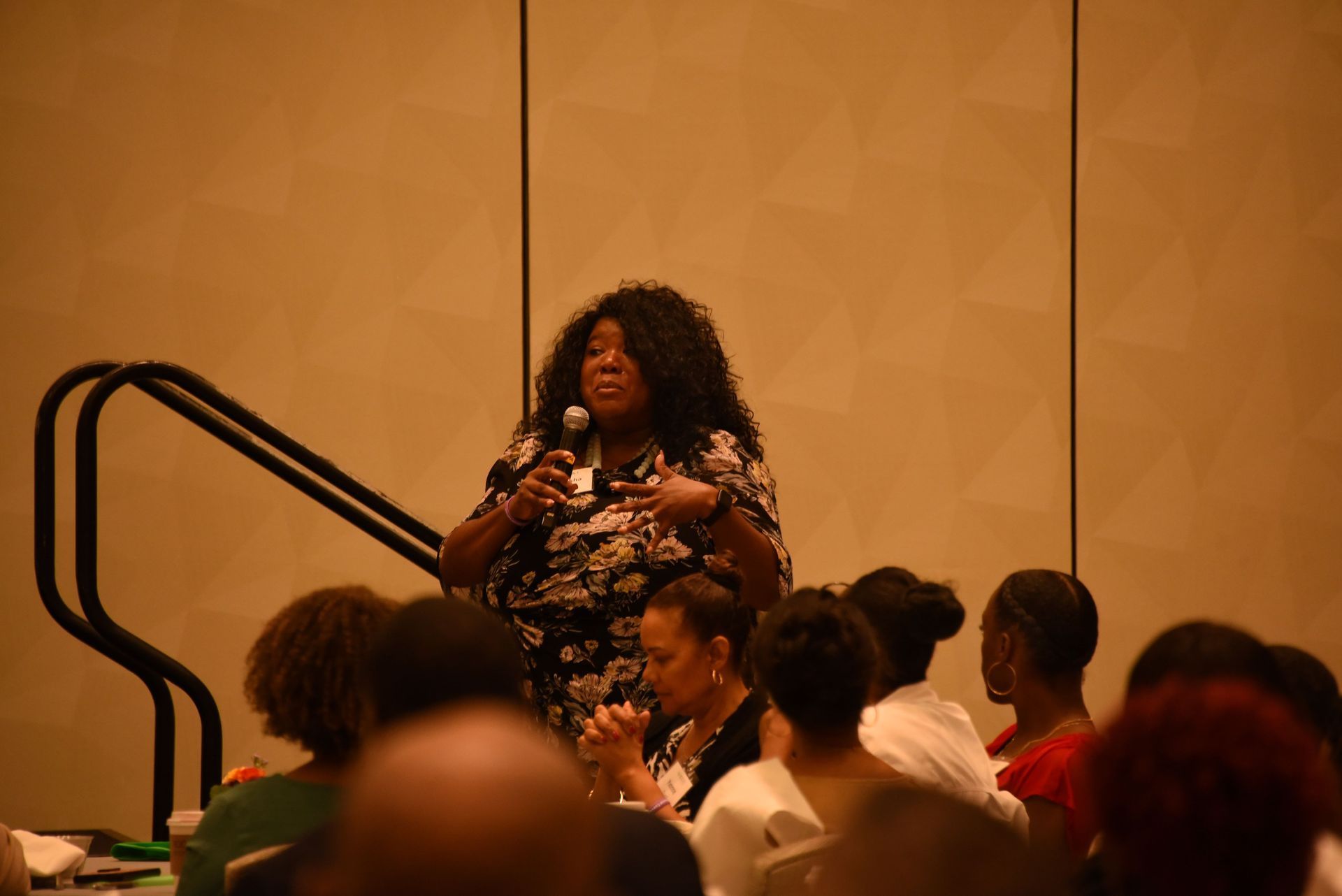 A woman is speaking into a microphone in front of a group of people.