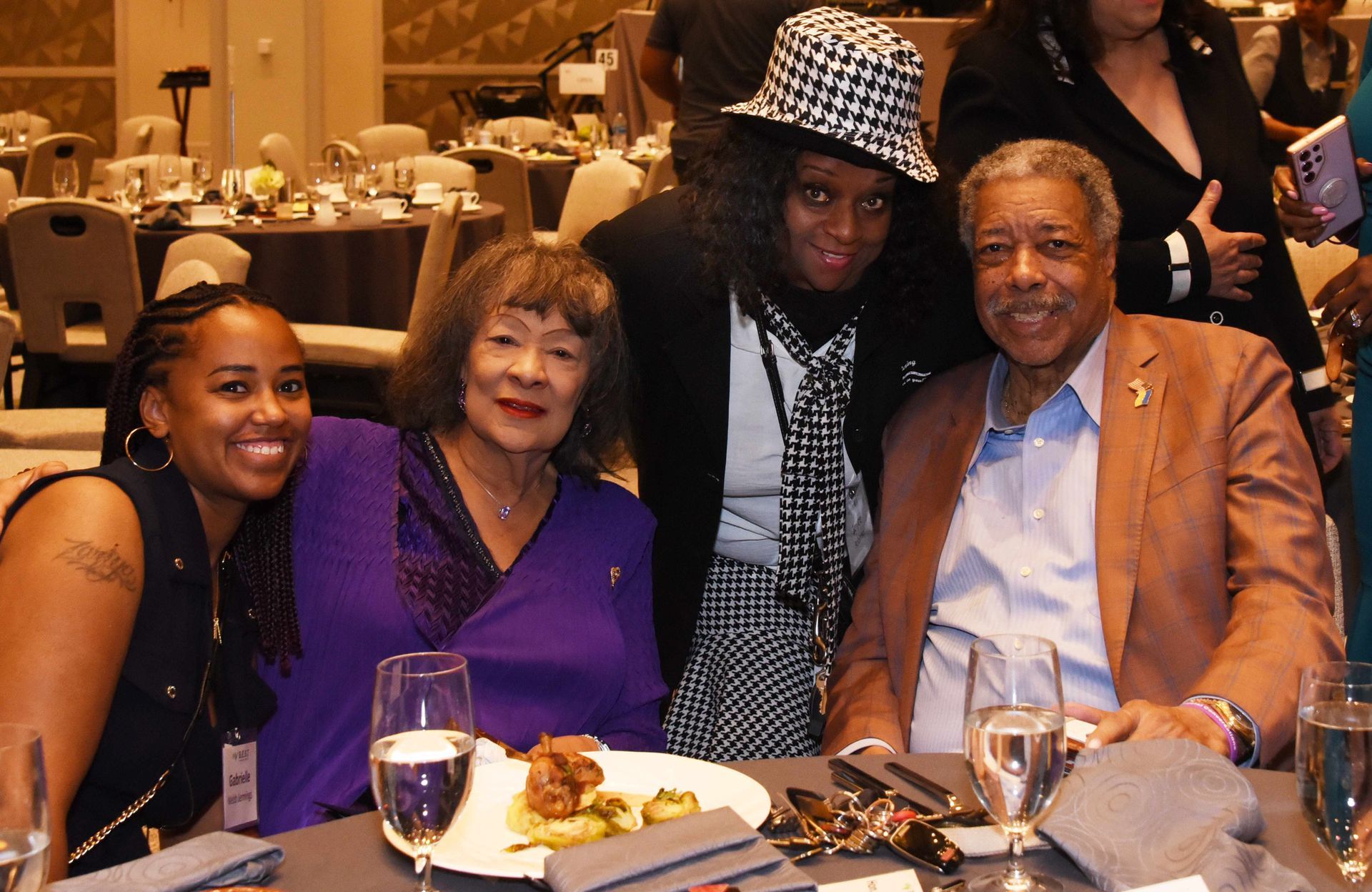 A group of people are posing for a picture at a dinner table.