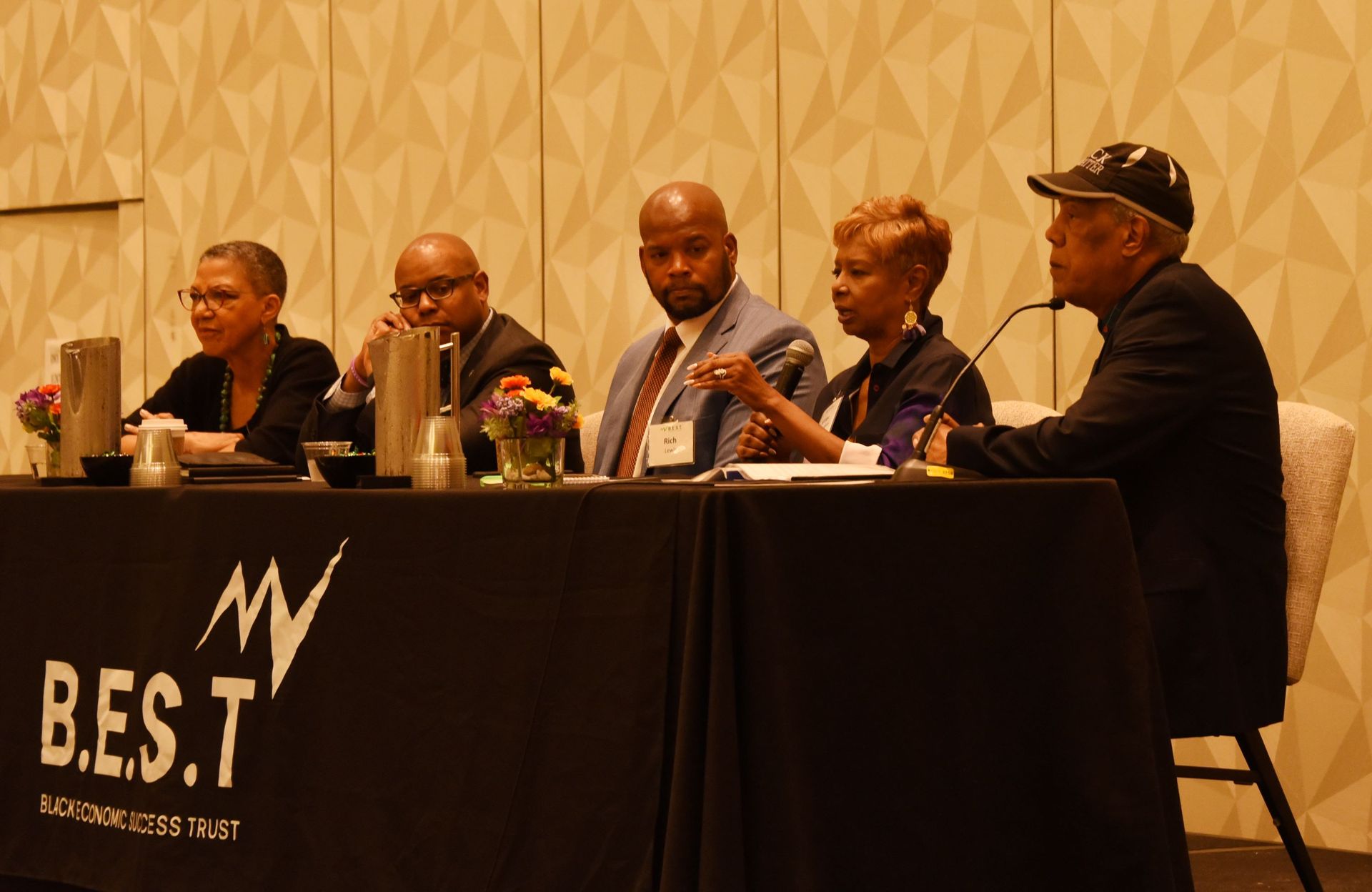 A group of people sitting at a table with a sign that says b.e.s.t.