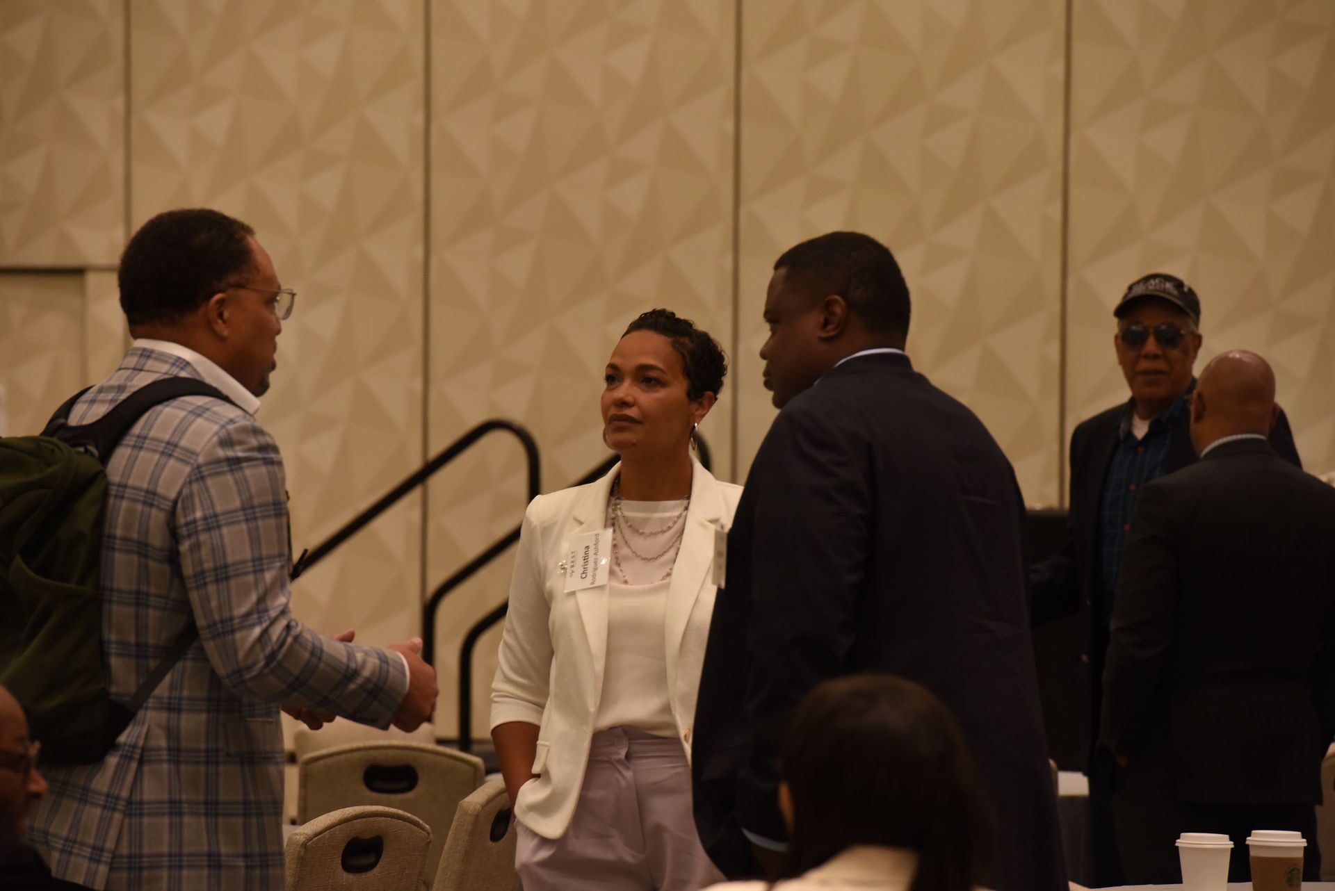 A group of people are standing in a room talking to each other.