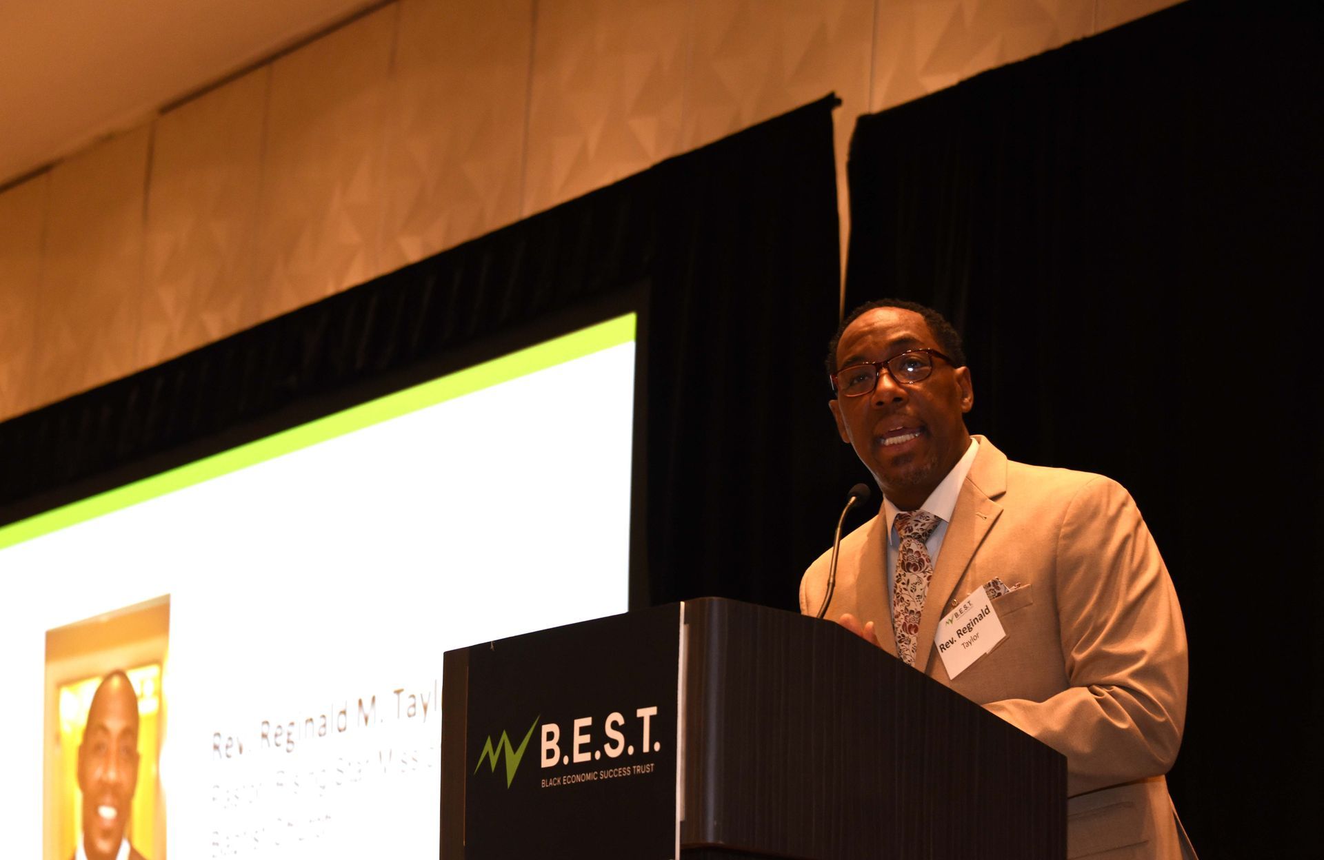 A man stands behind a podium that says b.e.s.t.