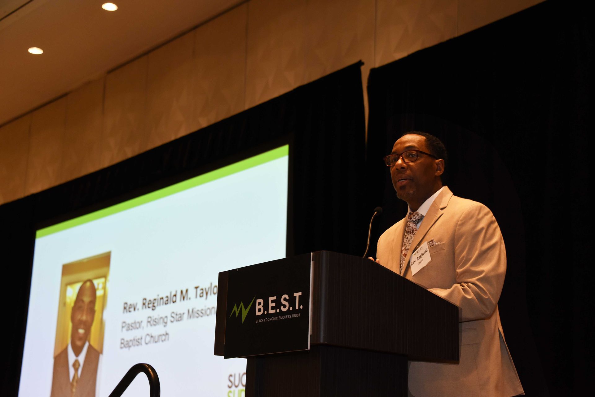 A man stands at a podium with a b.e.s.t. logo on it