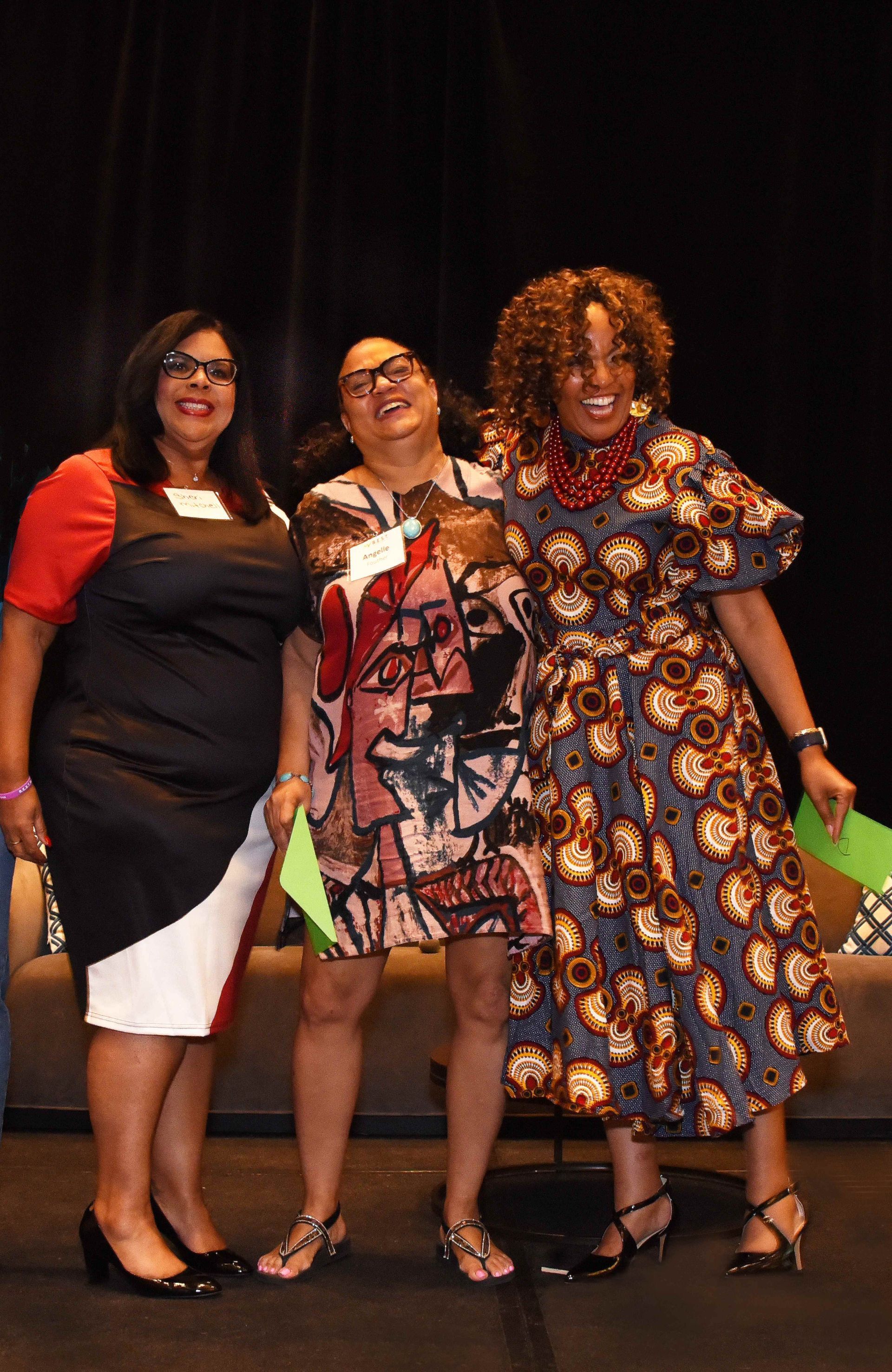 Three women are standing next to each other on a stage.