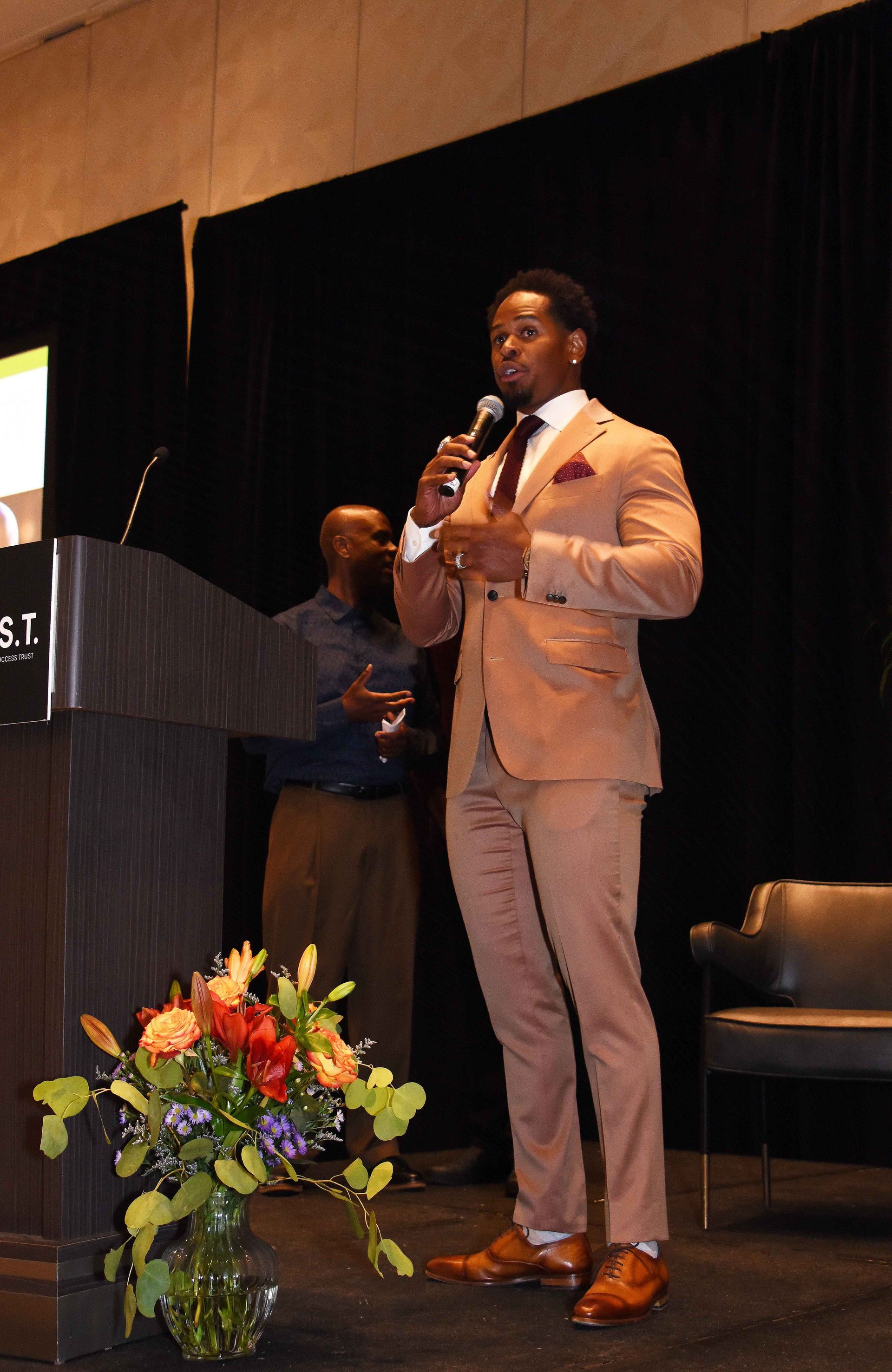 A man in a suit is speaking into a microphone