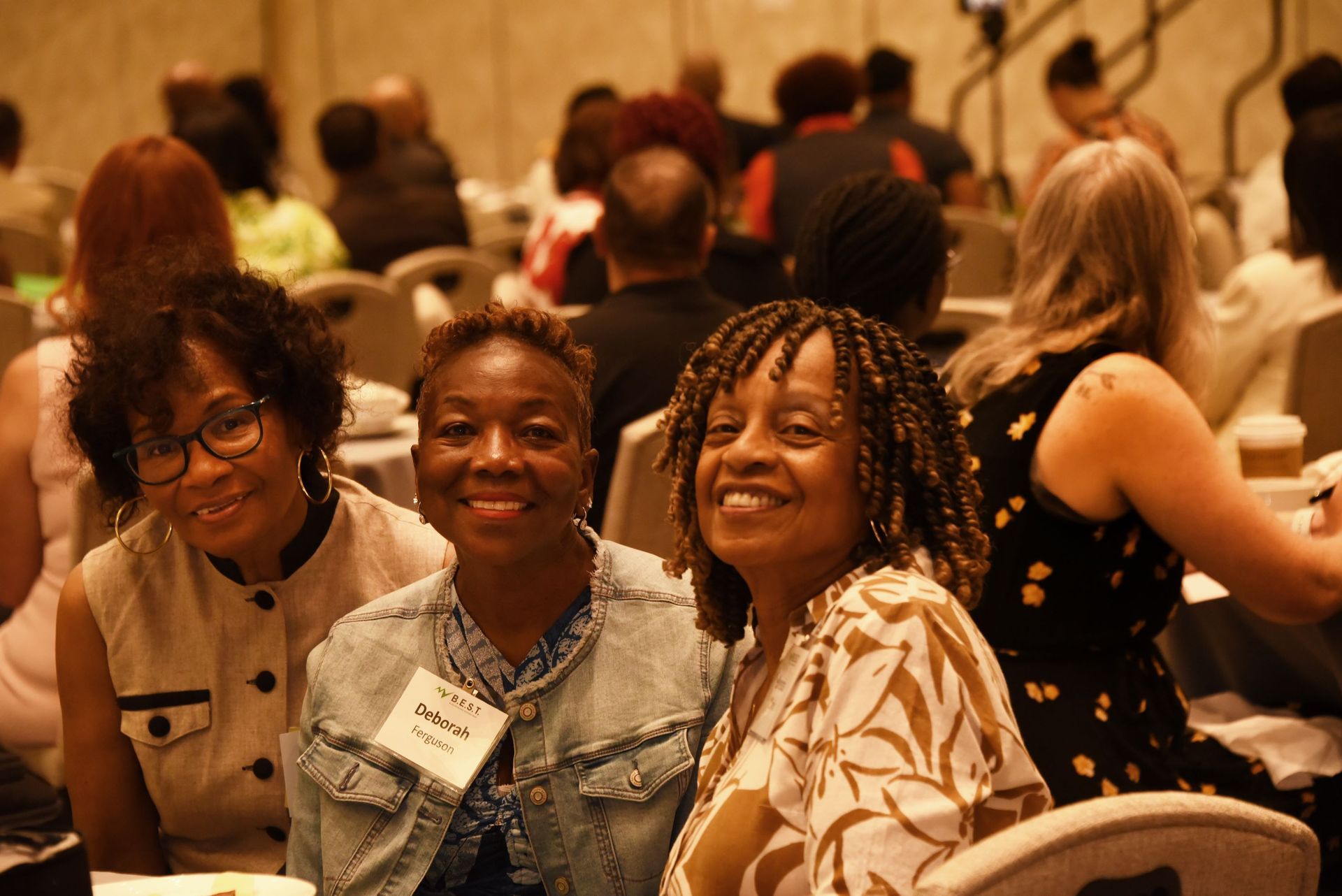 A group of women are sitting at a table smiling at the camera.