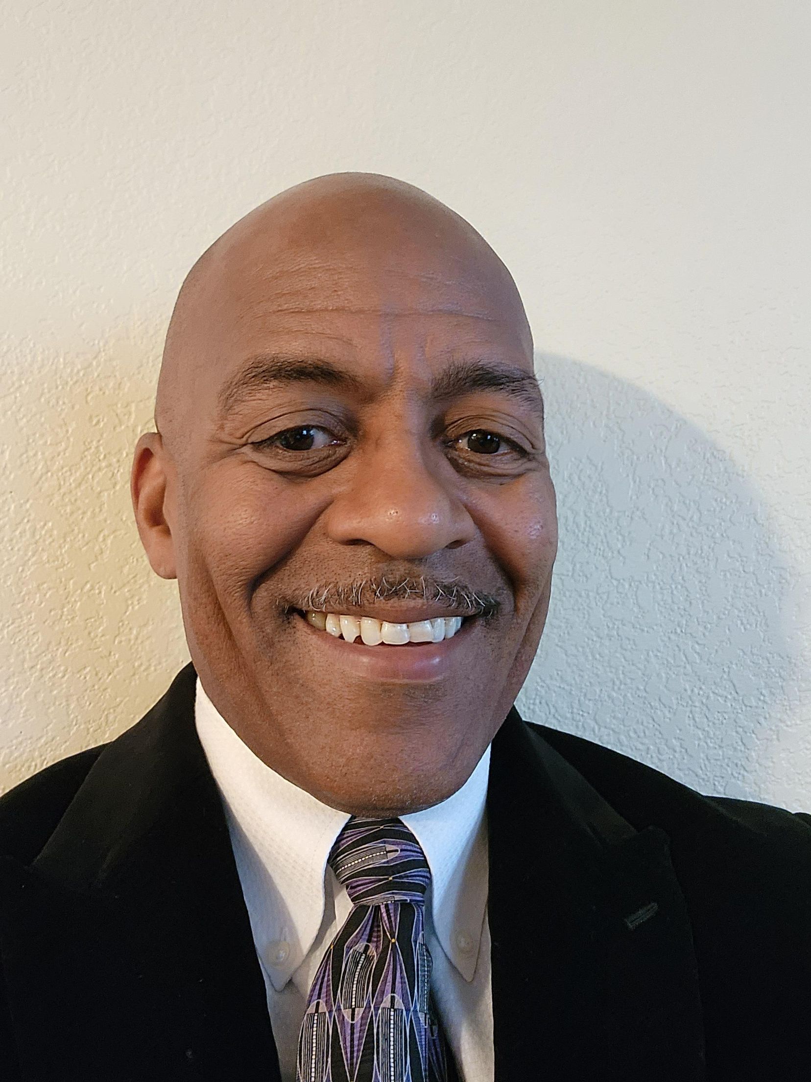 A man in a suit and tie is smiling for the camera