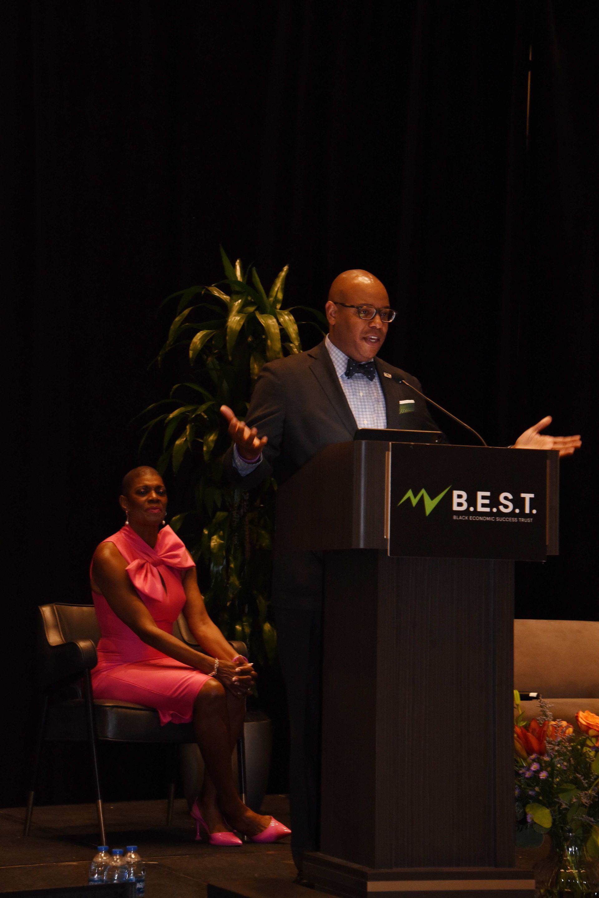 A man is giving a speech at a podium that says b.e.s.t.