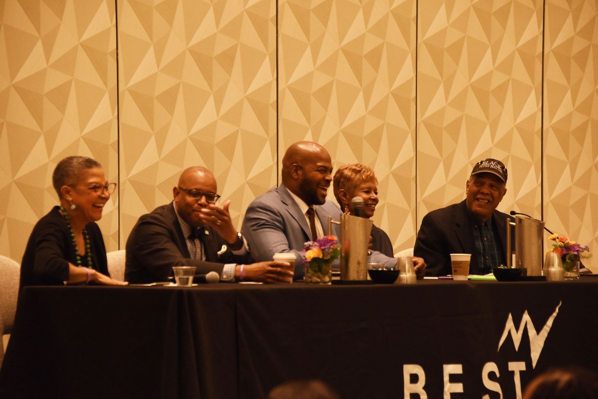 A group of people are sitting at a table with a sign that says my best.