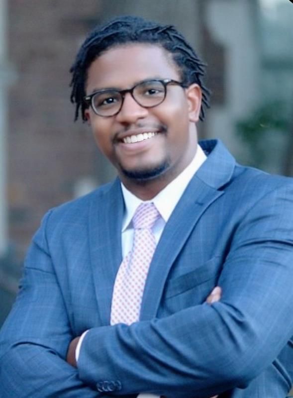 A man in a suit and tie is smiling for the camera