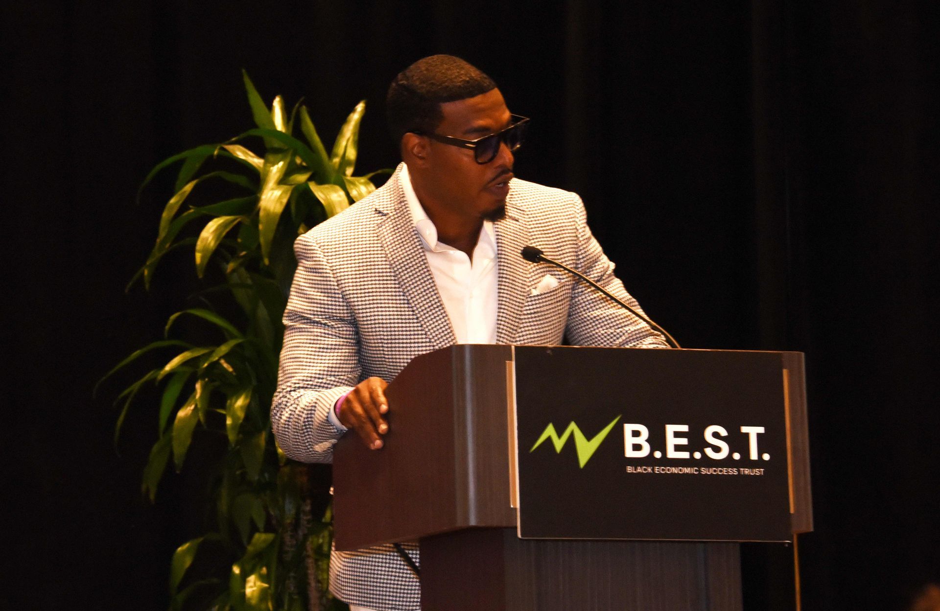 A man is giving a speech at a podium that says b.e.s.t.