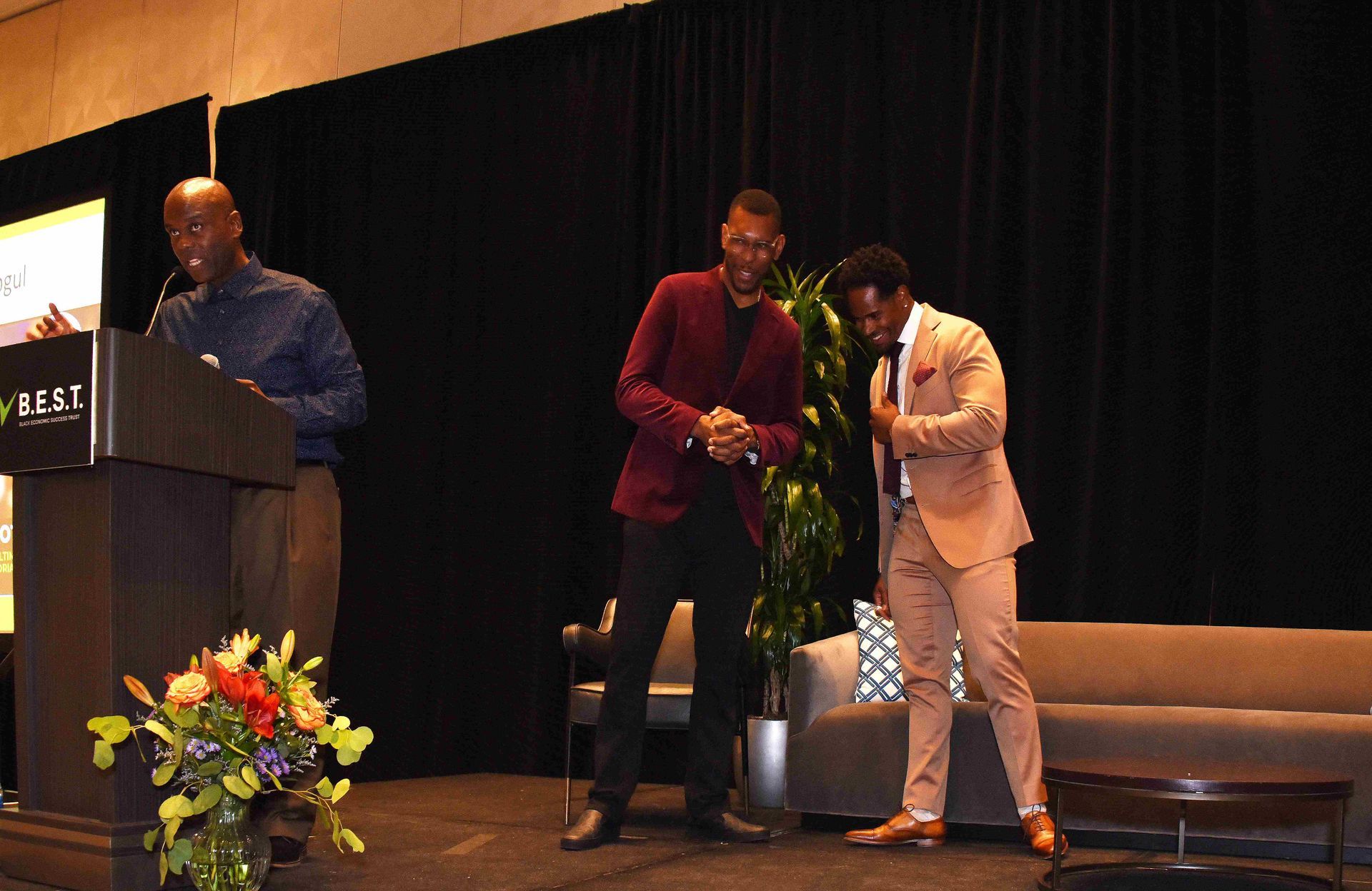 Three men are standing on a stage in front of a podium.
