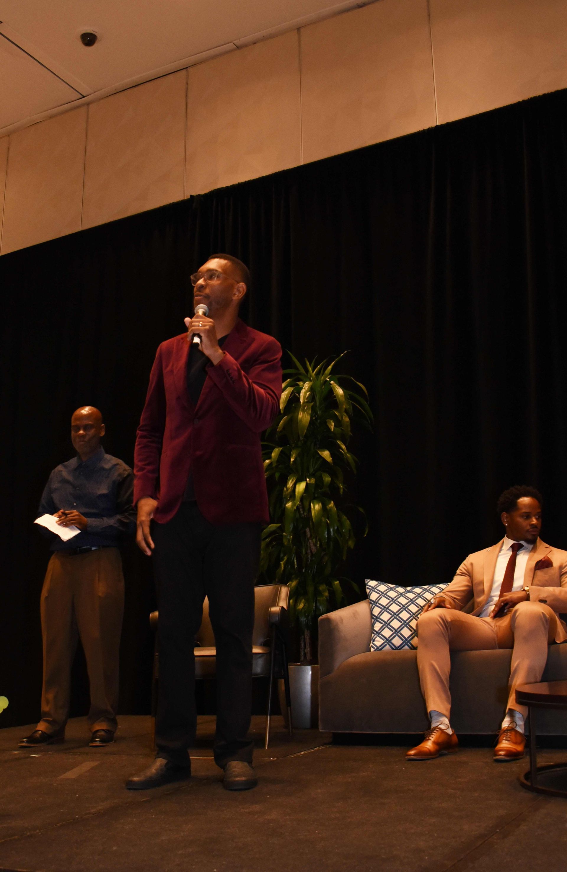 A man is standing on a stage holding a microphone.