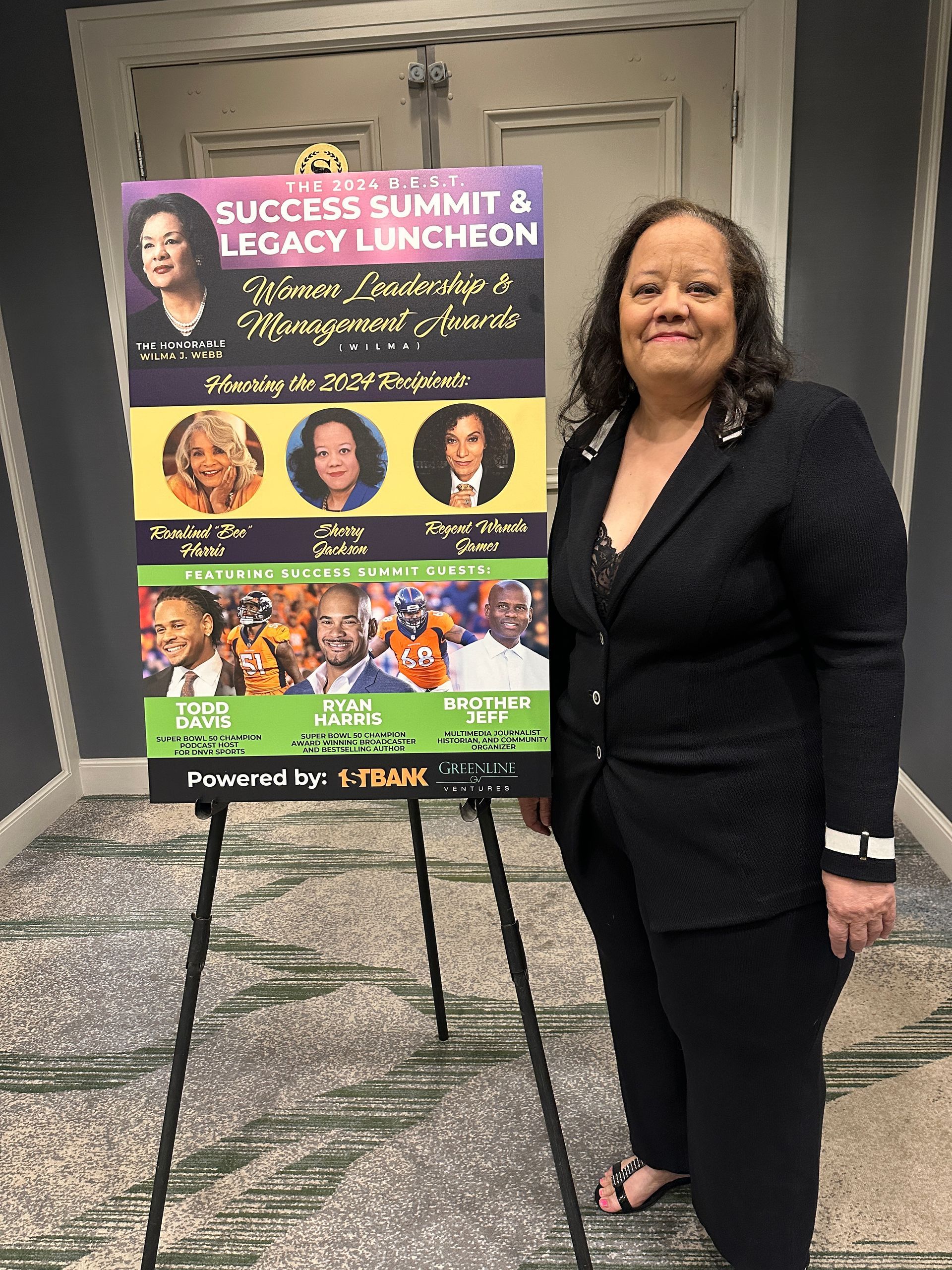 A woman is standing in front of a sign that says success summit & legacy luncheon