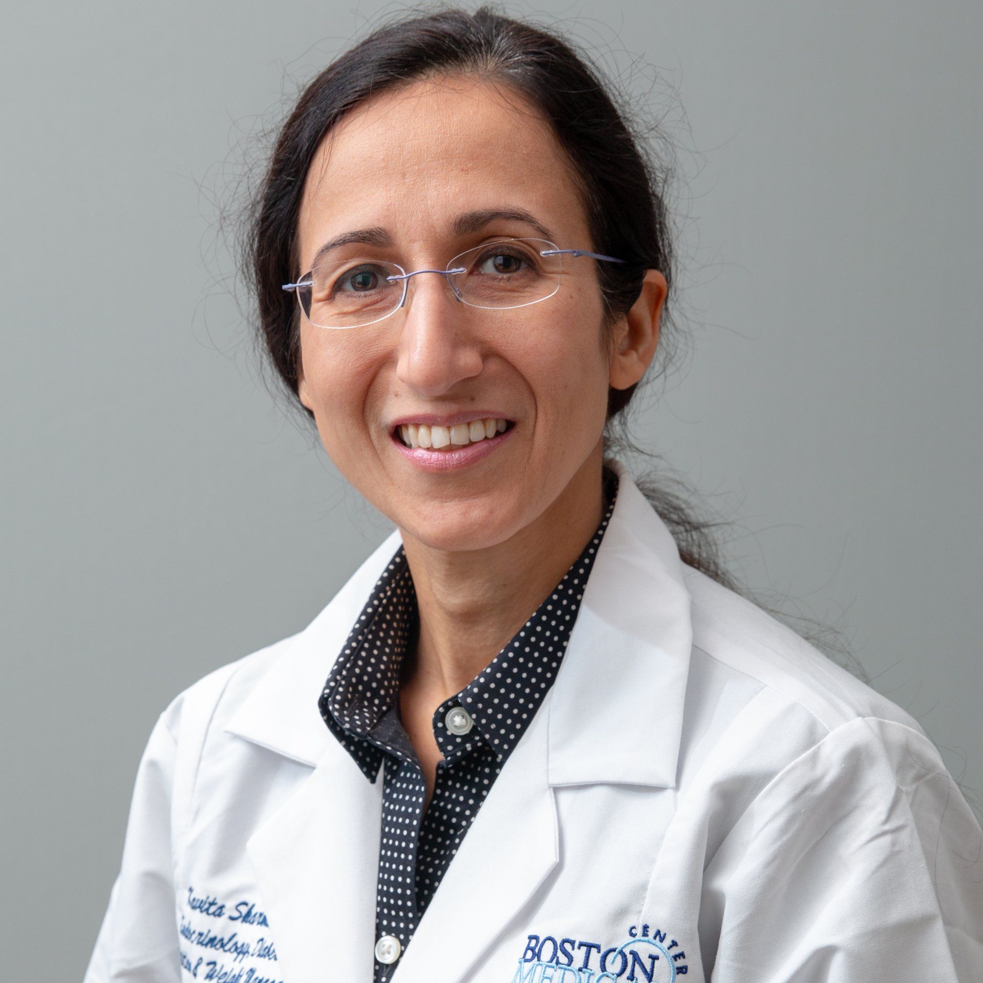 A woman wearing a white lab coat with the word boston on it
