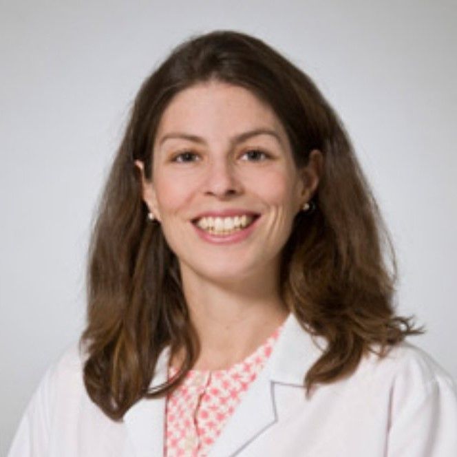 A woman in a white lab coat is smiling for the camera
