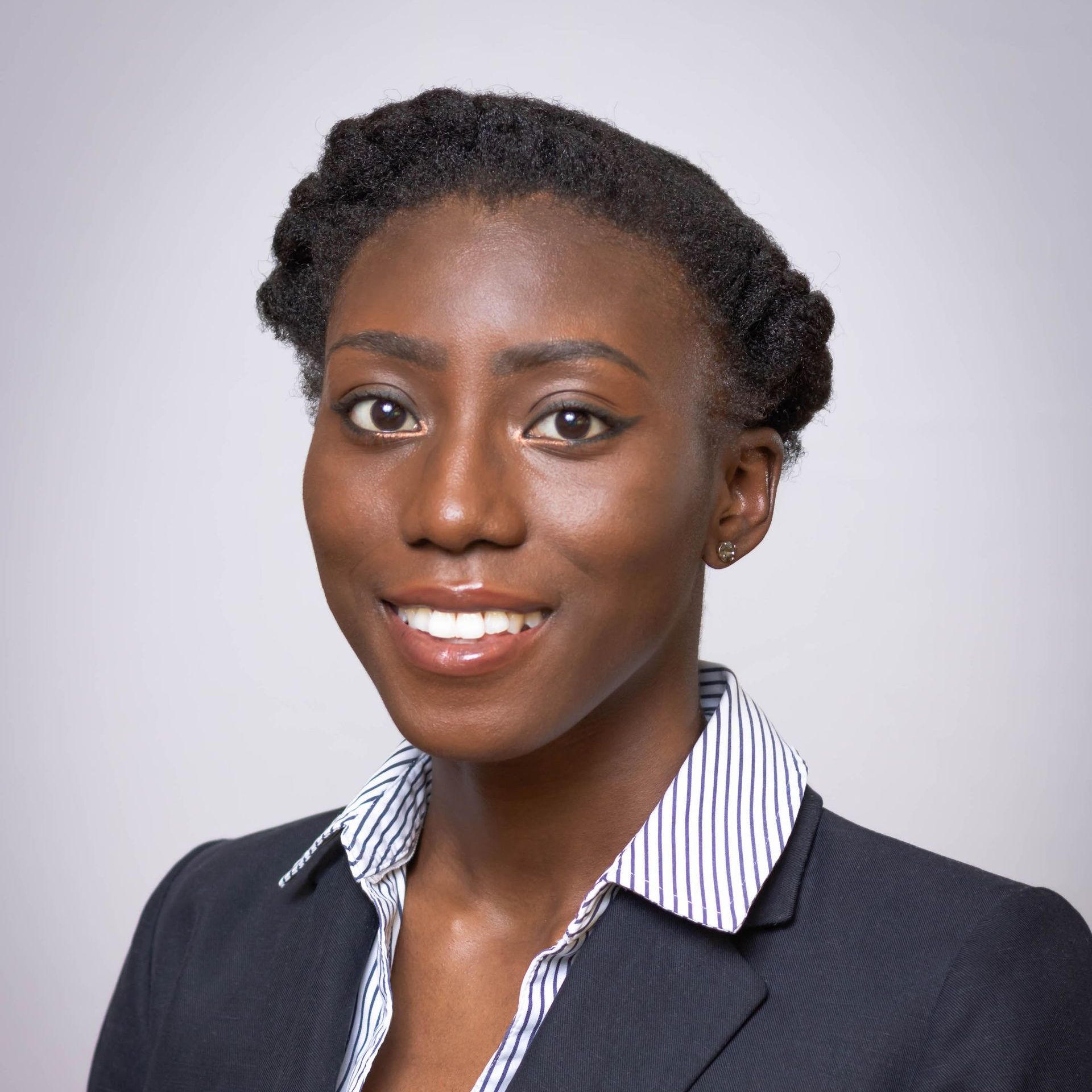 A woman in a suit and striped shirt smiles for the camera