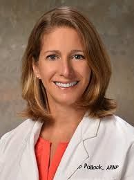 A woman in a white lab coat is smiling for the camera.