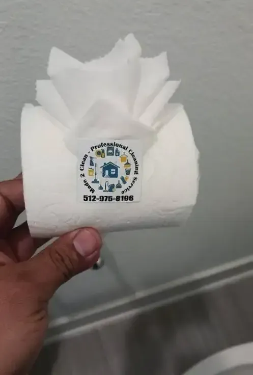 A person is holding a roll of toilet paper with a logo on it.