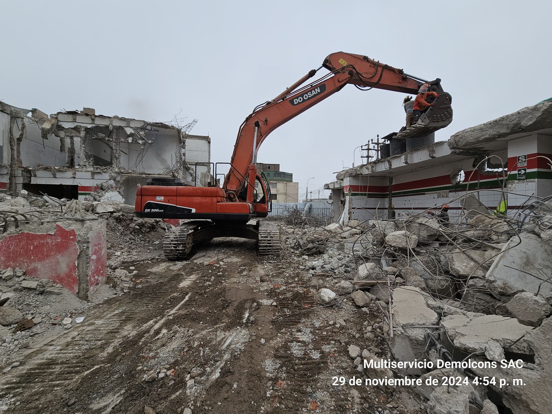 Una gran excavadora naranja está demoliendo un edificio.