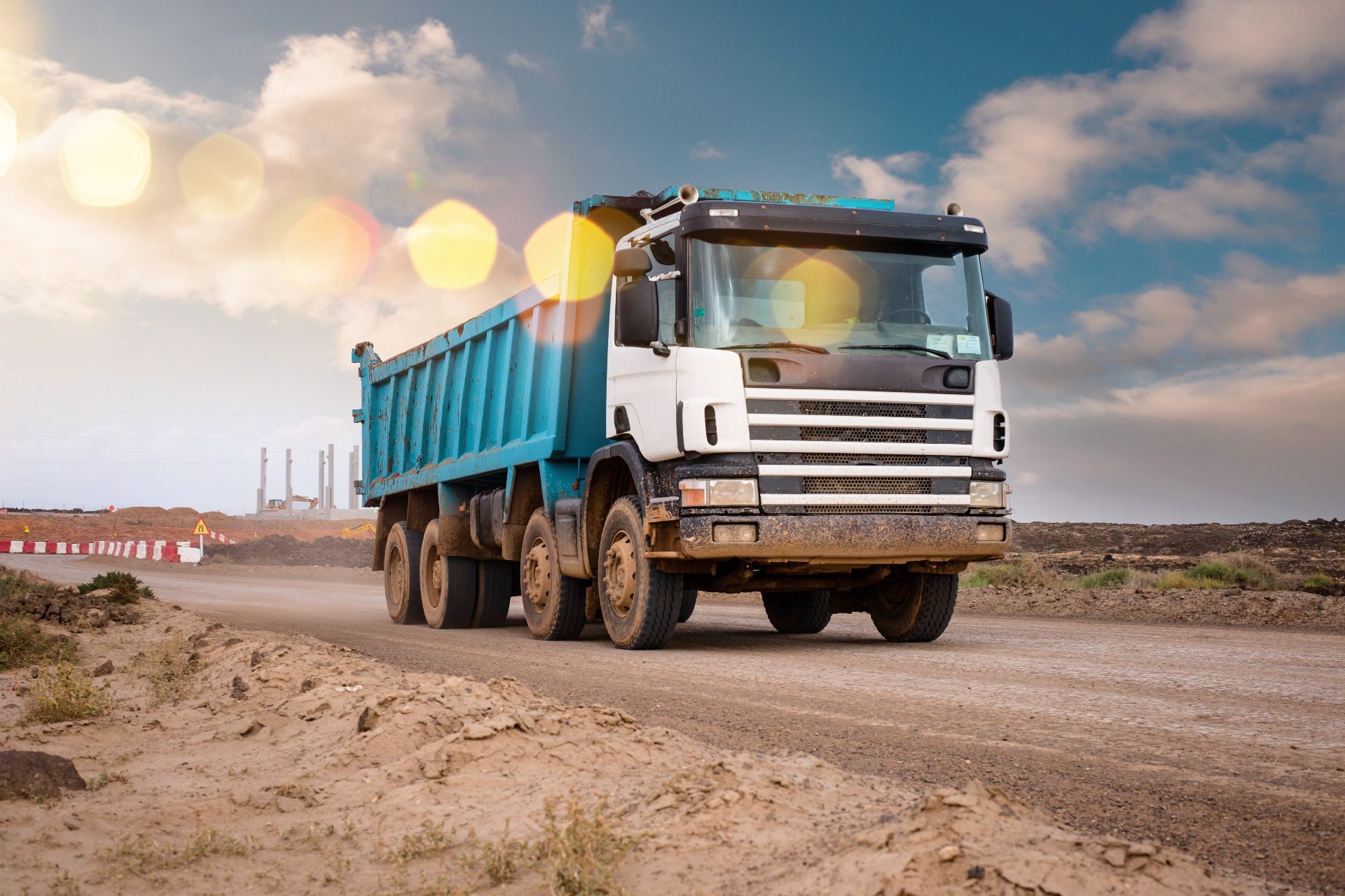 Un camión de volteo circula por un camino de tierra.